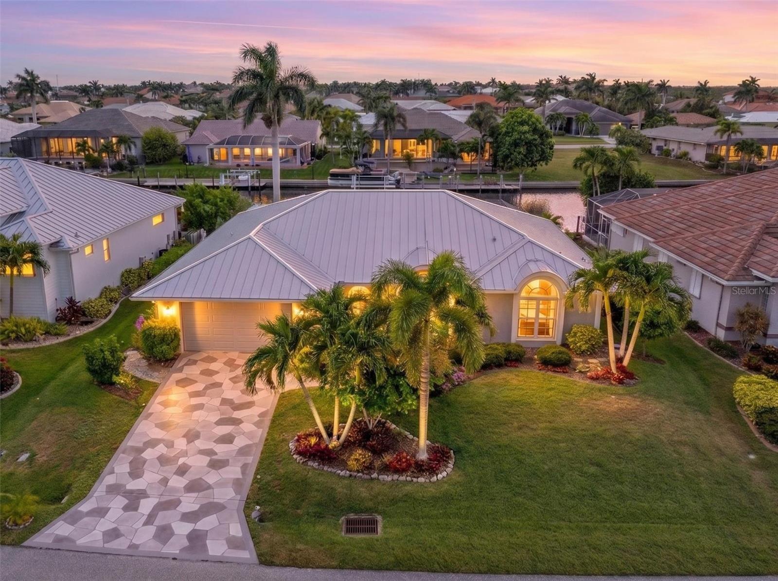 BOATER'S DREAM & NATURE LOVER'S PARADISE – Waterfront Pool Home with SAILBOAT QUICK ACCESS TO OPEN WATER!  Welcome to your private slice of paradise, where tropical beauty, waterfront living, and effortless entertaining come together. This exceptional waterfront pool home offers quick access to Charlotte Harbor, making every day feel like a vacation.  From the moment you arrive, the beautifully resurfaced decorative driveway and lush tropical landscaping create an unforgettable first impression. The meticulously designed butterfly garden, filled with identified host plants, transforms the property into a serene nature sanctuary where butterflies and birds flourish.  Step inside to soaring vaulted ceilings and be immediately captivated by the unobstructed water views. The spacious great room flows seamlessly into the dining area and beautifully updated kitchen, creating the perfect setting for both everyday living and entertaining. A skylight fills the kitchen with natural light, highlighting the abundant cabinetry, new appliances, double ovens, and induction cooktop—the true heart of the home.  The desirable split floor plan offers privacy for family and guests with three bedrooms and three baths, including a guest bath with direct lanai access. Ample closet space throughout ensures plenty of storage.  Designed to embrace Florida's indoor-outdoor lifestyle, multiple sliding doors lead to the expansive lanai and sparkling saltwater pool. The oversized screened lanai and spacious pool deck provide ample space for lounging, dining, and entertaining, while the outdoor shower adds convenience after a day on the water. Start your mornings with coffee overlooking the butterfly garden and spend your evenings unwinding in the peaceful ambiance of your private tropical oasis.  Enjoy complete peace of mind with numerous recent updates, including a new roof (2025), new garage door (2025), remodeled lanai and kitchen (2024), and impact windows and doors (2022).  Located in a peaceful, friendly neighborhood just minutes from Fisherman's Village and historic downtown Punta Gorda, you'll enjoy waterfront dining, boutique shopping, live entertainment, festivals, and endless community events. As an added bonus, the friendly La Mancha Court neighborhood hosts gatherings and social events throughout the year, making it easy to connect with neighbors and create lasting friendships.  Whether you're a boater, nature enthusiast, or simply searching for the ultimate Florida retreat, this extraordinary home delivers the lifestyle you've been dreaming of.  Schedule your private showing today and discover what true Florida waterfront living is all about.