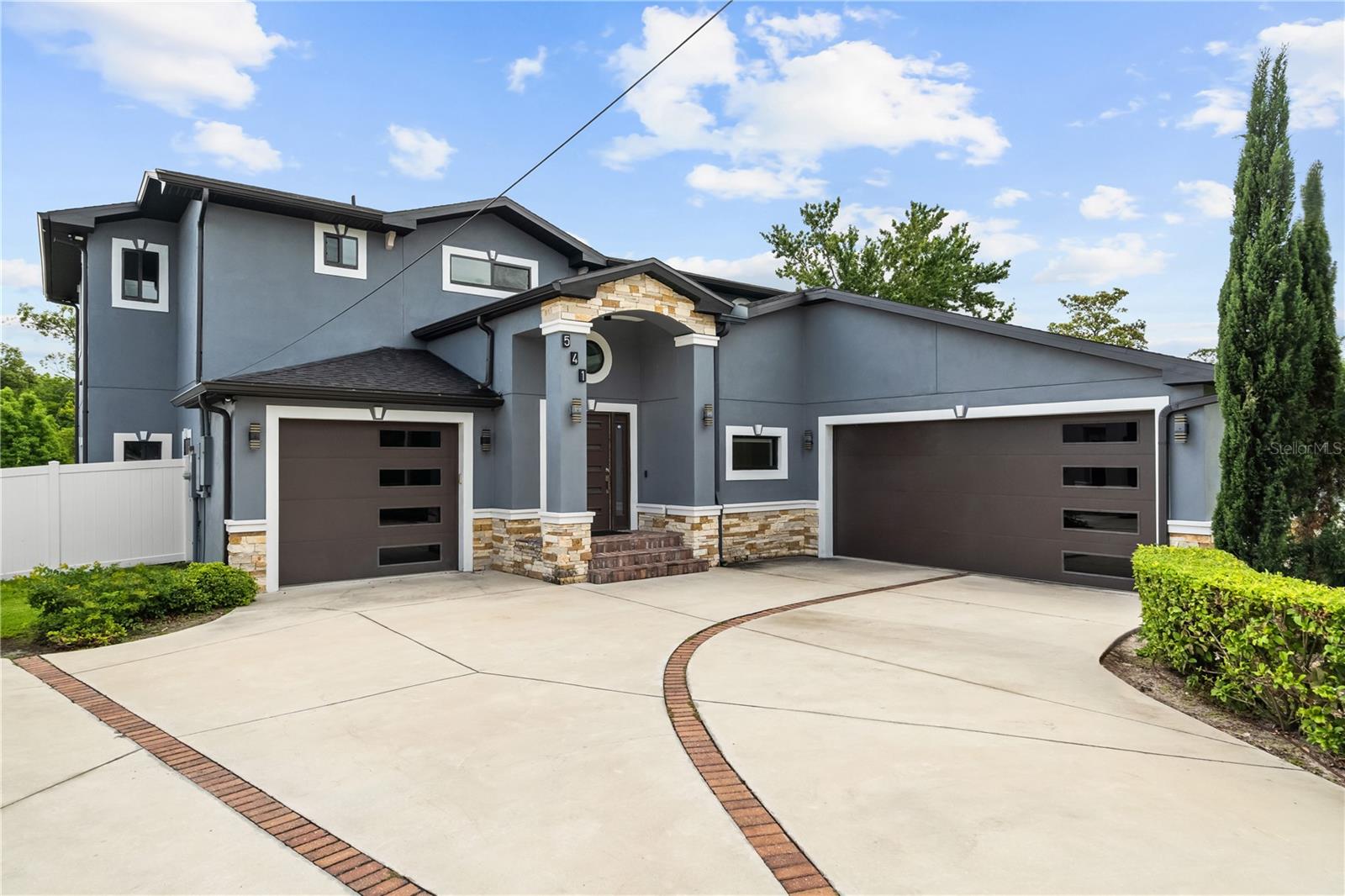 One or more photo(s) has been virtually staged. This CUSTOM contemporary home built in 2022 offers modern architecture, opulent interior design, NO HOA, and a highly functional floor plan featuring 3,100 square feet, 4 bedrooms, 3.5 bathrooms, a loft, GENERATION SUITE, and split 3-CAR GARAGE. From the moment you walk in, the floating staircase with frameless glass railings, soaring ceilings, oversized porcelain tile floors and open-concept layout immediately make this home truly unparalleled. The kitchen was designed to impress and function, featuring real wood cabinetry with soft-close doors and drawers, QUARTZ countertops, cooktop with downdraft exhaust, built-in convection oven/microwave, oversized farmhouse sink, designer LED lighting, and an oversized island built for entertaining. This home features a FIRST-FLOOR GENERATION SUITE with private bath, walk-in closet, separate HVAC system, and separate garage access, ideal for multigenerational living, guests, a second owner’s suite, or a private office setup. The upstairs owner’s retreat offers an expansive bedroom, dual walk-in closets, freestanding soaking tub, and walk-in shower with a dual function shower system. The loft leads out to a private balcony finished with low-maintenance Trex decking and modern cable railing. Aside from the countless builder upgrades, this home is full of after-market upgrades adding an outdoor private sanctuary featuring a 40+ foot patio with a custom TWO-STORY SCREEN ENCLOSURE, hot tub, and fenced in yard. This home was built with attention to efficiency and long-term durability, including double pane low-e windows, foam insulated block walls, radiant barrier roof sheathing, sound-deadening insulation, WiFi smart thermostats, epoxy garage floors, and extensive modern lighting throughout. Located in the highly sought-after Seminole County school district near Lake Brantley High, shopping, dining, Wekiva Springs, and major roadways, this is an opportunity to own a true custom home without the wait or cost of building new.