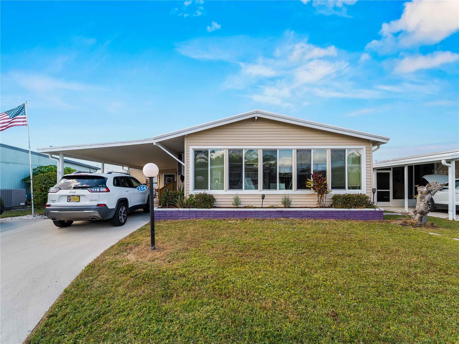 One or more photo(s) has been virtually staged. 154 Rarotonga Road in North Port, Florida, is a charming and well-cared-for manufactured home in the desirable 55+ waterfront community of Lazy River Village. There is no land rent—the community is resident-owned. This spacious 2-bedroom, 2-bath residence is filled with personality and functionality, offering bright, colorful living spaces and thoughtful updates throughout.

The enclosed Florida room spans the width of the home, creating a perfect space for relaxing with a book or enjoying the Florida sunshine from the comfort of indoors. The large primary suite includes ample closet space and an en-suite bathroom, while the second bedroom is ideal for guests, crafts, or an office. Both bathrooms feature tasteful finishes and plenty of storage.

Outside, the home offers a double driveway with a covered carport, a low-maintenance yard, and a cozy backyard patio area ready for grilling or lounging. The community itself is packed with amenities including a marina with boat slips, heated pool, tennis and pickleball courts, fitness center, and an active clubhouse with year-round events—all within minutes of Gulf beaches, shopping, and dining. Enjoy the added bonus of a golf cart included with the sale.

This is more than a home—it’s a lifestyle. Book your showing today and see what Lazy River Village living is all about!