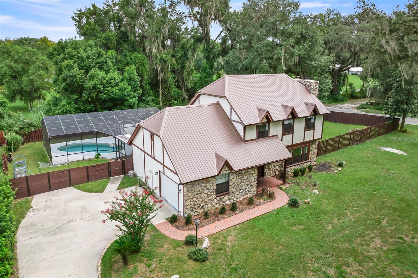 Tucked away on a quiet no-through-traffic road in the sought-after Thicket community, this striking Tudor-style home blends old-world architectural charm with a fully renovated interior — and a backyard built for resort-style living. Step inside to find luxury vinyl plank flooring flowing throughout the home. All three bedrooms and both full baths are upstairs for great privacy while the downstairs welcomes family and guests into the open and spacious living room with an updated half bath. The kitchen is a showstopper: rich espresso cabinetry, matching stainless steel appliances, quartz countertops, and a vaulted, beamed ceiling that gives the whole space an airy, elevated feel. Two electric fireplaces add warmth and character to the living areas, while the primary suite offers a peaceful escape with its own private balcony overlooking the grounds. Out back is where this property truly shines. A screened, in-ground pool with a shaded lanai and dedicated grilling area creates the ultimate spot for entertaining or unwinding — rain or shine, day or night. The fully fenced yard delivers total privacy, plus a one-of-a-kind two-story shed complete with an elevated playhouse and storage loft. There's even room for boat and RV parking, a rare find this close to town. Recent updates give buyers real peace of mind: dual-zone HVAC (2016 and 2022), metal roof (2022) and water heater (2022) mean the big-ticket items are already handled. Location seals the deal — under 3 miles to Ravine Gardens State Park, minutes from Palatka Golf Club, and easy access to the St. Johns River for boating and fishing. Small-town charm, big-time amenities, zero through-traffic noise.
Homes like this — Tudor character, a private pool oasis, and room for all your toys — don't sit long. Schedule your showing today.