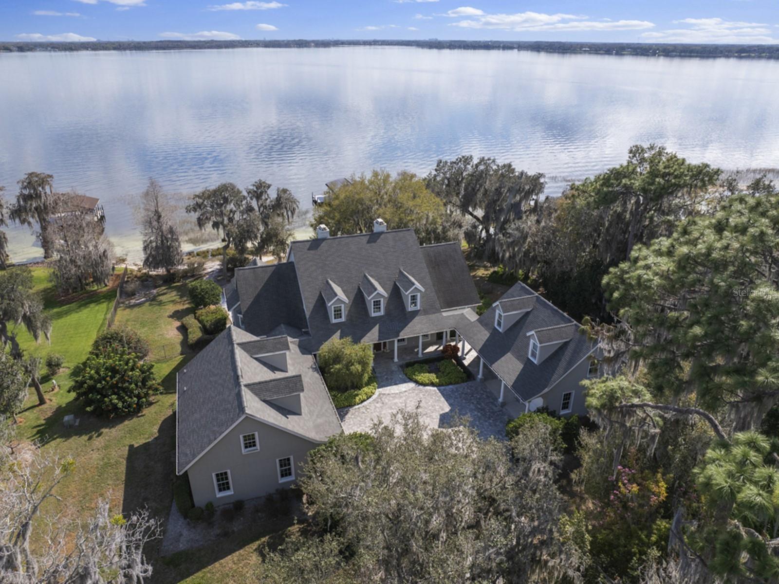 OVER 1.7 ACRES OF LAND ON LAKE BUTLER AND MORE THAN 230 FEET OF WATER FRONTAGE! Located on one of the most desirable streets in beautiful downtown Windermere, this custom-built home is positioned on over 1.7 acres with an amazing, wide open view of famed Lake Butler. As you enter the winding drive, you will arrive at this stunning residence created by renowned custom home builder Akers Construction. A sprawling front porch summons you home as you step into the interior space that is filled with top-of-the-line interiors and finishes. No detail has been overlooked. Unique architectural highlights include arched and paneled entryways and large windows that provide abundant natural light throughout the home. The open kitchen features tile floors, a large island, and additional counter space, ideal for sitting and sharing early morning meals. The family room offers a comfortable layout with beamed ceiling detail, as well as beautiful lake views from the window seat. The huge dining room is ideal for entertaining and sharing memorable holiday meals among friends and family.  A nicely appointed formal living room with lake views and a large fireplace is designed for comfort and entertaining. The large home office is private and perfect for quiet pursuits. The primary bedroom suite on the first floor is spacious and offers a private sitting area with lovely lake views. The primary bath boasts his and her vanities, marble details, a walk-in shower, a soaking tub, and a lovely stained-glass window. There is an additional room off the primary bedroom hall that would be ideal for a gym, nursery, additional closet space or more. Upstairs, three ensuite bedrooms are expansive, each with a large closet and beautifully designed bathroom. Two over-sized garages offer parking for four cars as well as depth and height for additional storage. Above the west garage you will find a fully equipped guest apartment with living /dining area, kitchenette, bedroom, and full bath. The ground level of this garage has a workshop area and a steel beam with hoist for use with heavy equipment. The east garage features an unfinished second floor, useful for additional living space or insulated storage. On the lower level of the home, adjacent to the pool, you will find a large recreation room for entertaining and a pool bath. Outside, the sparkling pool includes a spa and cascading waterfall. The pool is also accessible by a sweeping stairway leading down from the screen porch and upper patio off the living room and family room. And what will surely be your favorite place to spend sunsets is the more than 230 feet of pristine water frontage and private white sand beach, inviting you to experience the true wonder of Florida living. The home also features one of the largest, private boat docks on the Butler chain with three covered boat lifts, perfect for a boat enthusiast. The dock roof supports solar panels that partially power the home. Another bonus of this home is the large under-house storage area for boating and outdoor equipment. Schedule your tour of this breathtaking property today! NOTE - PRICE INCLUDES ALL THREE ADJOINING PARECELS WHICH EQUATE TO 1.72 ACRES.