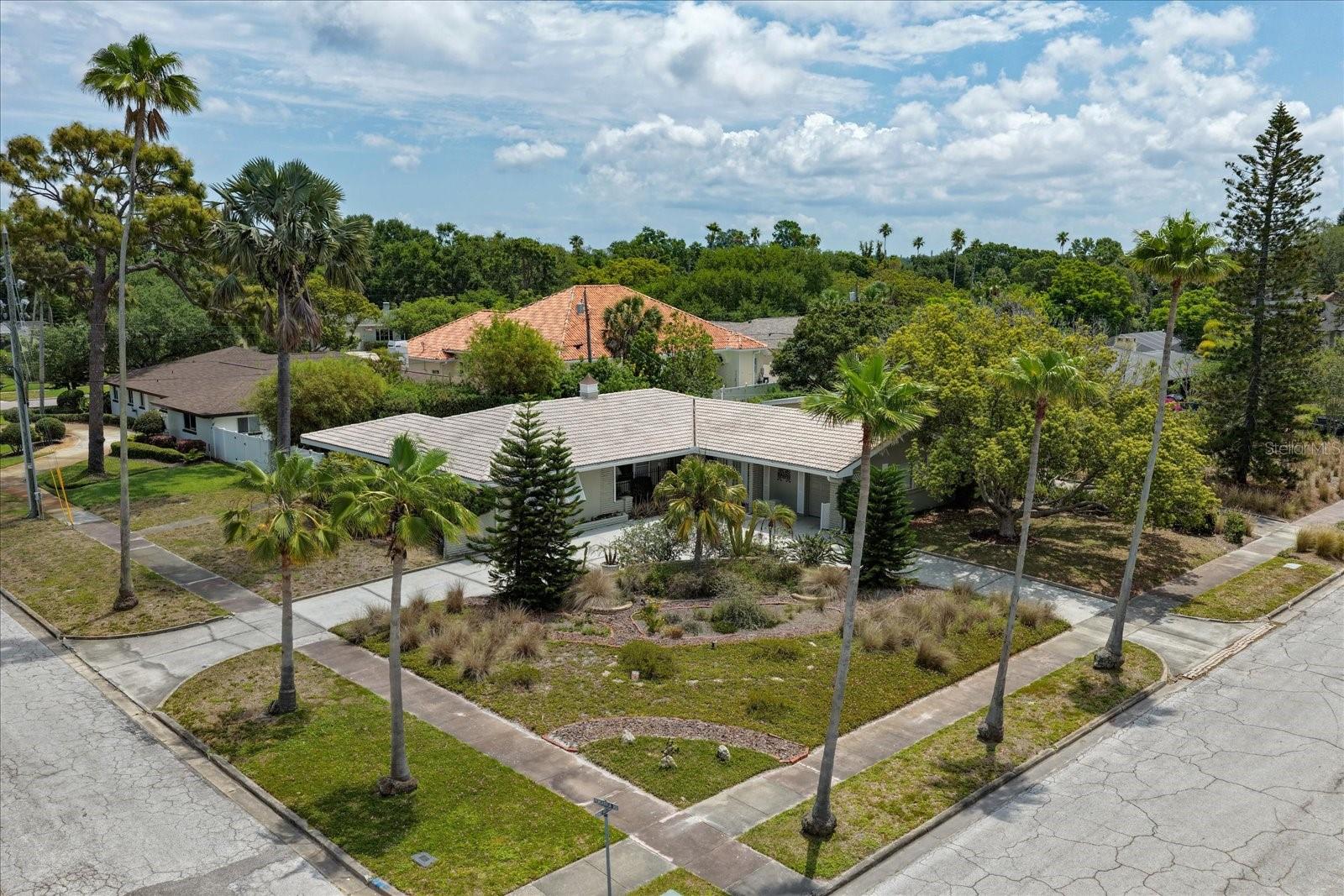 Tucked on a corner lot in the heart of Belleair, this unique custom-built home radiates timeless character and storybook appeal. A circular drive and thoughtfully designed zero-scaped yard filled with native, easy-care plantings create an inviting cottage feel, while nearby parks, scenic walking paths, and waterfront green spaces along the Intracoastal offer a tranquil, picturesque setting just moments from your door. Inside, the home is warm, welcoming, and rich with artistic flair. A versatile, well-designed layout offers flexibility for modern living, highlighted by a spacious kitchen with stainless steel appliances, and a cozy breakfast area to enjoy serene views of a lush courtyard. The desirable split-bedroom plan provides privacy, with each of the three bedrooms featuring its own adjoining bath. Three spacious living areas create the perfect backdrop for entertaining or relaxing, enhanced by custom pillars, detailed trim, crown molding, baseboards, and a blend of 18" tile and wood flooring throughout. Additional spaces include a utility room and a bonus room ideal for a home office, guest space, or extra storage, with the potential to easily convert back into a second garage. French doors lead to a screened porch, where a flagstone patio and charming brick walkways extend the living space outdoors. Thoughtful extras such as a security system, storm shutters, an interior cedar closet, and a dedicated garage work area add both comfort and function. Ideally located near boutique shopping, dining, two private golf courses, and the area’s renowned white sand beaches, this one-of-a-kind home offers a rare blend of character, convenience, and coastal charm.