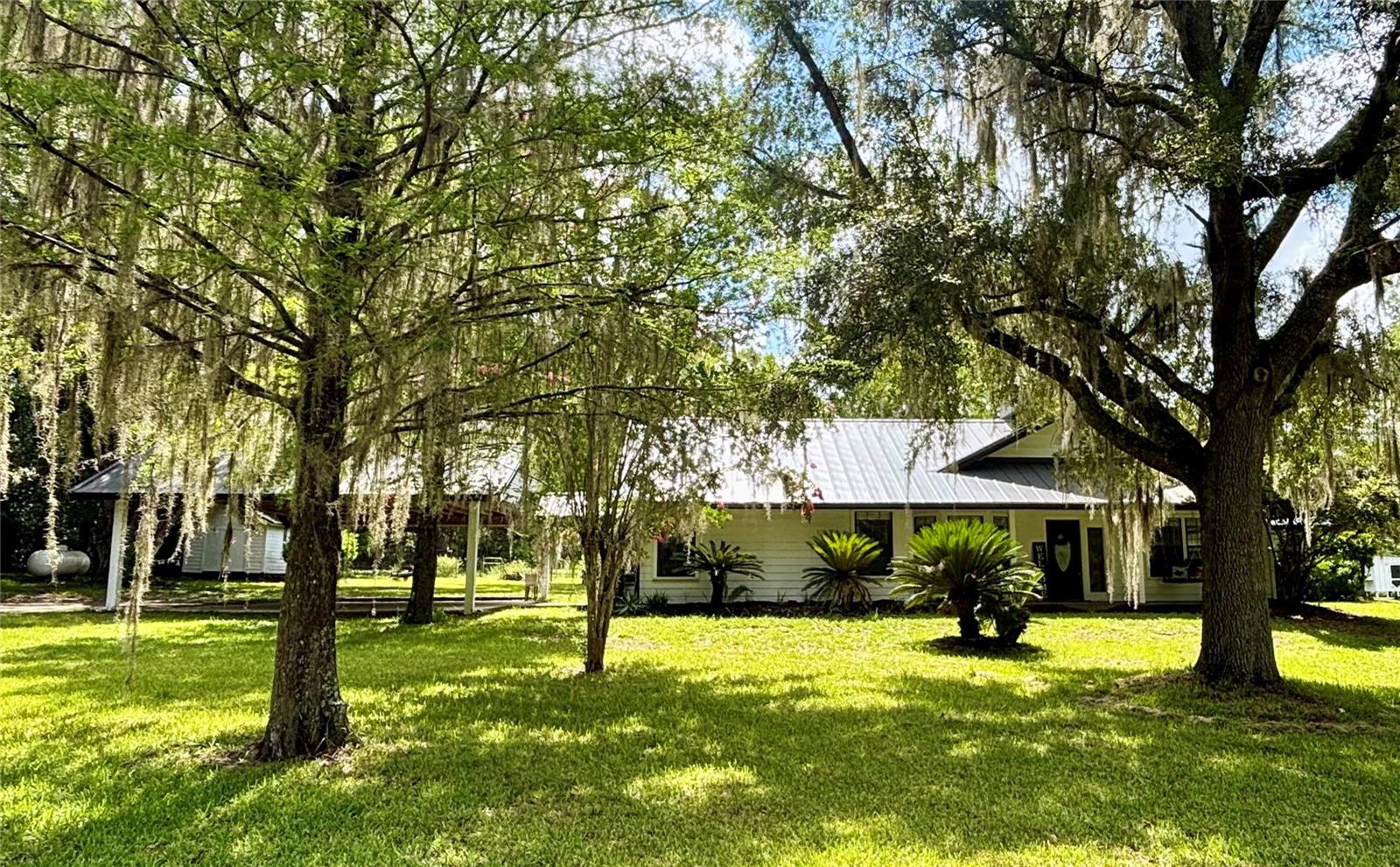 Escape to the peaceful country lifestyle you've been dreaming of with this charming 3-bedroom, 2-bath cedar home nestled on 6.3 picturesque acres. Surrounded by majestic, mature trees that provide abundant shade and privacy, this beautiful property offers the perfect blend of comfort, character, and room to grow.

Relax on the inviting front porch with your favorite beverage as you unwind on the porch swing and take in breathtaking sunset views. Inside, you'll be welcomed by a stunning custom double-sided brick fireplace that serves as the centerpiece between the spacious living room and dining room, creating warmth and charm throughout. An additional great room offers plenty of space for gatherings, entertaining, or simply relaxing.

The spacious kitchen features abundant cabinet storage and a cozy breakfast nook, making it the perfect place to start your day. The light-filled primary suite boasts soaring ceilings, generous walk-in closets, and large windows that bring the beauty of the outdoors inside.

Outside, the possibilities are endless. The 6.3-acre property is fenced and cross-fenced with open pasture, making it ideal for horses, livestock, or creating the small farm you've always envisioned. Additional features include a 40-year lifetime metal roof, oversized two-car carport, storage shed/workshop, whole-house generator, and an incredible canopy of mature trees that enhance the property's natural beauty.

Conveniently located just off County Road 1474, this desirable property offers an easy commute to Gainesville, Ocala, and Jacksonville while allowing you to enjoy the peace and tranquility of country living. Whether you're looking for a hobby farm, a private retreat, or your forever home, this exceptional property is ready to make your country dreams a reality.