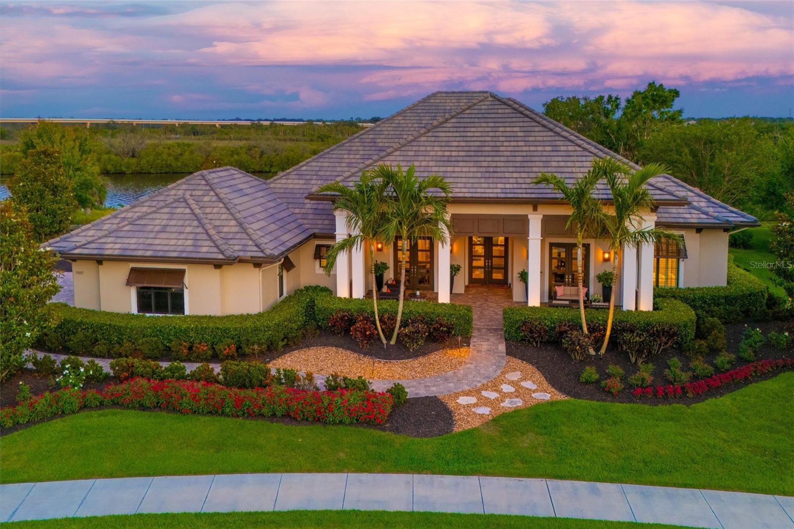 Florida waterfront living at its absolute finest. Perfectly positioned along the scenic Manatee River within the exclusive, gated community of The Islands on the Manatee River, this extraordinary estate delivers a rare blend of privacy, elegance, and resort-caliber living—all just moments from the area’s most sought-after destinations. Enjoy the best of both worlds: a tranquil riverfront setting with convenient access to the vibrant lifestyle hubs of Lakewood Ranch Main Street and Waterside Place, as well as the premier shopping, dining, and entertainment of University Town Center. Whether it’s upscale dining, boutique shopping, or lively community events, everything you need is just a short drive away. From the moment you arrive, the home makes a lasting impression with lush, manicured landscaping and a grand covered front porch featuring dual sitting areas—perfect for welcoming guests in style. Inside, soaring 25-foot ceilings and dramatic floor-to-ceiling pocket sliding glass doors create a seamless connection between indoor and outdoor living, filling the home with natural light and capturing stunning water views. Designed for both everyday comfort and elevated entertaining, the residence offers three spacious bedrooms plus a versatile bonus room complete with a wet bar and beverage refrigerator. The chef’s kitchen is a true showpiece, appointed with premium appliances including a GE Profile Sub-Zero refrigerator and freezer, along with a Wolf range, oven, and microwave. The expansive primary suite serves as a private retreat, featuring a dedicated sitting area, dual custom walk-in closets, and a spa-inspired bath with a soaking tub and an oversized walk-through shower with dual entrances, multiple shower heads, and a built-in bench. Step outside to your personal resort-style oasis overlooking the river and protected natural preserve. Enjoy a heated pool with a tanning ledge, a relaxing spa, and a covered lanai with roll-down screens—ideal for year-round outdoor living. A private walkway leads to your dock, complete with a brand-new (Q1 2025) 20,000-lb boat lift, accommodating large vessels for effortless access to the Gulf. Additional highlights include a three-car side-load garage with custom cabinetry, a new AC system (2024), and a prime location with convenient access to Sarasota, St. Petersburg, and Tampa. This is a rare opportunity to own a refined riverfront estate offering unmatched privacy, luxury, and connectivity to the very best of Florida’s Gulf Coast lifestyle.
