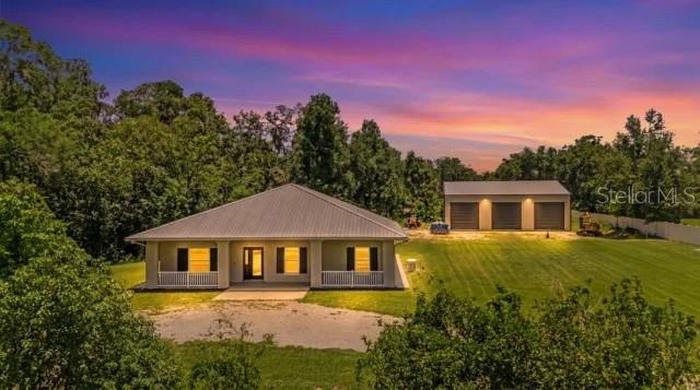 This DeLand property delivers something that's becoming increasingly difficult to find—a beautifully updated home paired with an extraordinary 3,600-square-foot red iron building that has the flexibility to become whatever your lifestyle demands. Whether you're running a business, expanding a collection, storing RVs, boats, classic cars, recreational vehicles, equipment, or even aircraft, creating the ultimate workshop, or designing an oversized man cave unlike anything you've seen before, this remarkable structure is built to handle it. Constructed less than two years ago, the 60' x 60' x 18' building features three oversized 14' x 14' doors, making it as functional as it is impressive.

Hidden from the road at the end of a long private driveway, the home enjoys a peaceful setting on 2.02 acres with no HOA and Agricultural zoning, offering privacy while remaining just minutes from Interstate 4, shopping, restaurants, and the charm of Downtown DeLand. The property itself invites outdoor adventure, with room to ride four-wheelers, explore your own acreage, or simply enjoy the freedom that comes with having space of your own.
Inside, the home is crisp, clean, and thoughtfully updated with 2,304 square feet, three bedrooms, two and a half bathrooms, fresh interior and exterior paint, a durable metal roof, and new luxury vinyl plank flooring throughout the bedrooms, kitchen, and living areas. A welcoming front porch that spans the length of the home creates an inviting first impression, while the full-length screened back porch provides a peaceful place to relax and enjoy the private surroundings. The kitchen serves as the heart of the home with a center island featuring a built-in cooktop, bar seating for casual meals, and an open flow into the main living spaces that makes gathering with family and friends feel effortless. Just off the kitchen, the laundry room includes a new washer and dryer that convey with the home. Adjacent to it, a separate room with shelving and countertop space creates an oversized walk-in pantry that keeps everything organized and within easy reach. Conveniently located off the living room, the beautifully remodeled half bath showcases marble flooring, a granite vanity, and a striking modern backsplash that adds a sophisticated designer touch.


The primary suite offers a relaxing retreat with a cozy nook that's perfectly suited for a home office, reading area, or quiet sitting space. French doors open directly onto the screened back porch, creating a seamless connection to the outdoors. The ensuite bathroom features a spacious walk-in shower, a large jetted soaking tub, and separate custom walk-in closets designed with both comfort and organization in mind.

A brand-new white vinyl fence enhances privacy along the front of the property, while the expansive front porch and screened back porch provide inviting places to relax and enjoy the peaceful surroundings. A Generac generator adds an extra layer of confidence during Florida's storm season, and the exceptional detached building continues to set this property apart with the kind of space that's rarely available. Combining a beautifully maintained home with an incredible workspace and the freedom of acreage living, this property offers a lifestyle that's every bit as impressive as the structure that defines it.
