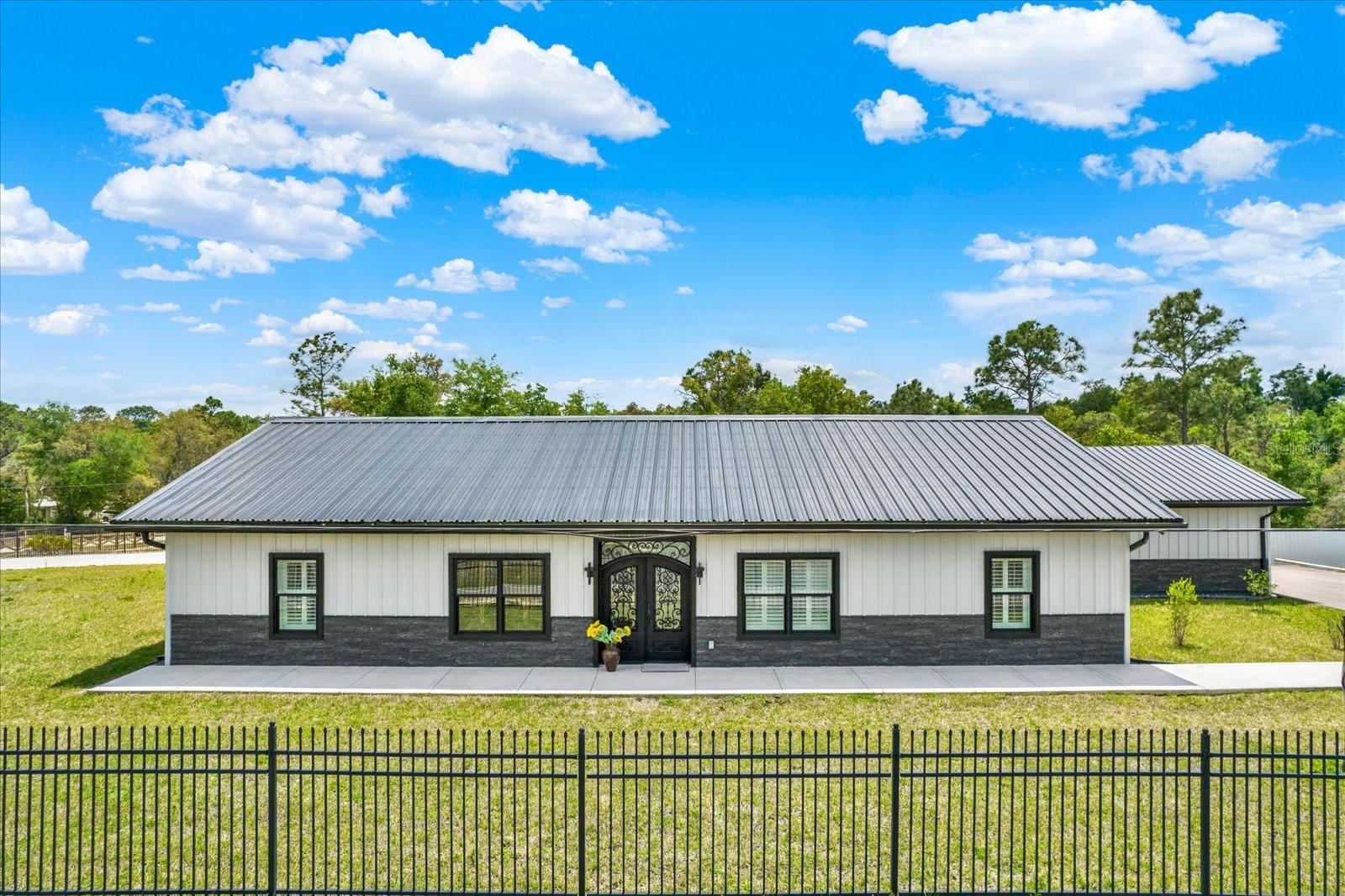 Virtually Staged. One or more photo(s) have been virtually staged. Welcome to your dream home! This brand new, energy-efficient modern barndominium with a 26-gauge commercial metal roof seamlessly blends luxury, craftsmanship, and functionality. Situated on a 0.98-acre corner lot, the property features a fully gated exterior with two entrances, providing both privacy and convenience. From the moment you arrive, you'll be captivated by the wrought iron gates, impressive front doors, and stunning curb appeal. Step inside to discover a spacious open-concept home adorned with high-end finishes and premium building materials throughout. The gourmet kitchen is the heart of the home, complete with granite countertops with waterfall edges, custom cabinetry, a copper backsplash, GE Caf appliances, a ZLINE gas range with a griddle, a commercial hood with infrared heat lamps, and a coffee bar equipped with a pot filler--perfect for entertaining or everyday family living. Luxury continues throughout with concrete epoxy flooring, porcelain sheets in bathrooms, plantation shutters, designer lighting, upgraded doors, and windows. The home offers three spacious bedrooms, 2.5 bathrooms, an office, and a large rear flex space with access to a potential fourth bedroom or private mother-in-law suite, ideal for guests or flexible living options. The master suite is a true retreat, featuring a custom-built closet with built-ins and drawers, tray ceilings, dual vanities with gold hardware, a jetted soaking tub, and a spacious walk-in shower with porcelain finishes. Every detail has been thoughtfully designed, creating a cohesive and stunning aesthetic throughout the home. Additional highlights include a large mudroom and laundry room, an oversized garage with overhead storage, and air-conditioned attic space. The property is currently located in flood zone X and offers central access to U.S. Highway 301, State Road 50, and Interstate 75, making commuting and travel effortless. The fully fenced backyard provides a peaceful retreat, perfect for outdoor enjoyment. This home truly has it all--luxury, functionality, and timeless design. Don't miss the opportunity to make this one-of-a-kind modern barndominium yours. Schedule your private showing today and envision yourself living the lifestyle Richardson has to offer!