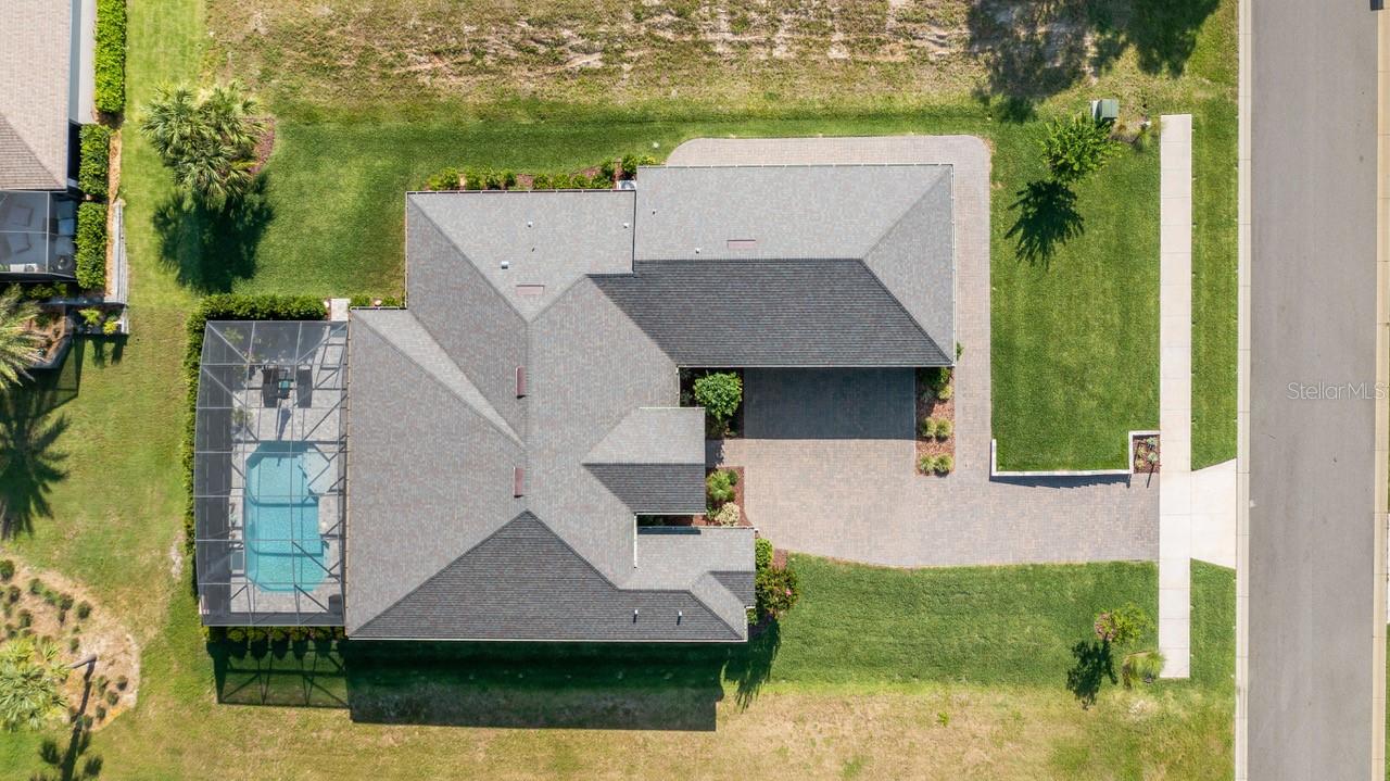 Why wait months for new construction when this exceptional custom-built home is ready to enjoy today? Perfectly positioned on a premium oversized 0.32-acre golf-view homesite, this meticulously upgraded residence offers 3 bedrooms, 3 bathrooms, a private office/den that can easily serve as a fourth bedroom, and an impressive collection of luxury features throughout. From the moment you enter, you'll be captivated by the soaring 10-12 foot ceilings and expansive open-concept design that creates an atmosphere of elegance and comfort. The thoughtfully designed floor plan seamlessly connects the family room, dining area, and gourmet kitchen, making it ideal for both everyday living and entertaining. Natural light pours through oversized windows accented with plantation shutters, highlighting the home's upscale finishes and custom details. The family room serves as a stunning centerpiece, featuring a custom white oak built-in bookcase and a beautiful wood tray ceiling that adds warmth and character. Designed to impress, the chef's kitchen boasts custom cabinetry, granite countertops, an oversized 5' x 8' island, a spacious pantry, and abundant prep and storage space. Whether hosting guests or preparing family meals, this kitchen delivers both style and functionality. The private owner's suite offers a true retreat, tucked away in its own wing of the home. This luxurious sanctuary features dual walk-in closets and a spa-inspired bath complete with dual vanities, a walk-in shower, and a relaxing soaking tub. Guests and family members will appreciate the well-designed secondary bedrooms, including a private en-suite bath for the third bedroom and convenient access to a full bath for the second bedroom. The flexible office/den provides the option for a fourth bedroom, hobby room, or dedicated workspace. Step outside and discover resort-style outdoor living at its finest. The expansive lanai features a fully equipped outdoor kitchen, three electric privacy screens, and a sparkling 24' x 14' in-ground heated pool overlooking picturesque golf course views—creating the perfect setting for relaxation and entertaining year-round. Additional conveniences include a spacious laundry room with extra cabinetry and a second refrigerator. Car enthusiasts, hobbyists, and outdoor adventurers will appreciate the exceptional garage space, including a 35' x 25' three-car garage with epoxy flooring and a built-in vacuum system, plus a golf cart garage with door for added accessibility. The oversized garage easily accommodates full-size trucks, workshop space, and recreational equipment. Combining superior craftsmanship, thoughtful design, premium upgrades, and an outstanding golf course setting, this move-in-ready home offers a rare opportunity to enjoy the benefits of luxury new construction without the wait. Harbor Hills is a gated community on over 900 acres with access to Lake Griffin.