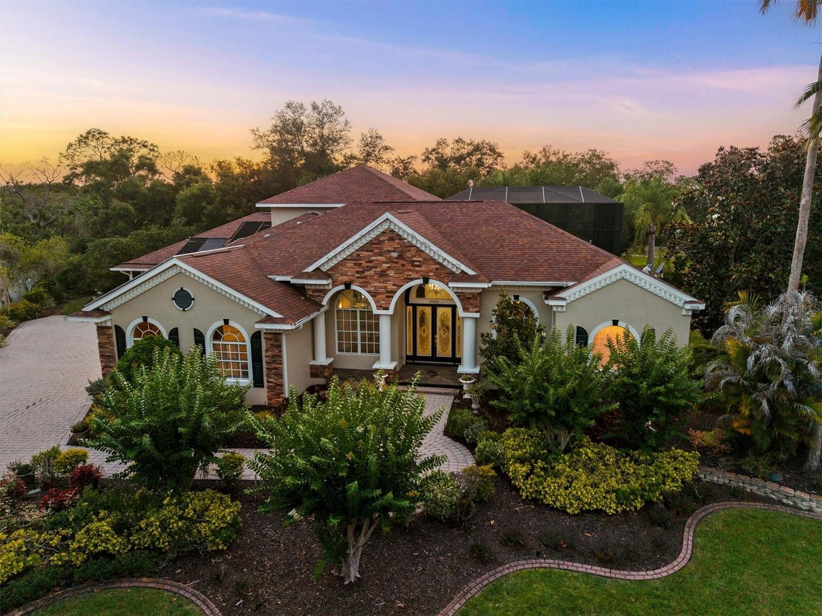 Tucked away at the end of a quiet cul-de-sac, this NEWLY RENOVATED estate unfolds like a private retreat designed for those who value peace, space, and timeless sophistication. Set across 1.32 acres, the home is surrounded by mature landscaping and preserve views, the 5-bedroom, 4-bath residence creates a sense of seclusion that feels worlds away while still remaining close to everything. From the moment you arrive, the property invites you into a lifestyle centered around comfort, connection, and effortless indoor-outdoor living. Sunlight pours through expansive windows, illuminating thoughtfully REDESIGNED interiors where elegance meets warmth. The RECENTLY RENOVATED kitchen serves as the heart of the home. With brand new counter tops, this kitchen has transformed beautifully and is perfectly refreshed to bring people together, or slow mornings with coffee overlooking the pool and preserve views. The living room has been TRANSFORMED into a calming, sophisticated space with soaring ceilings and an open flow that enhances the home’s inviting atmosphere. Both the upstairs flex suite and downstairs primary suite have been COMPLETELY REIMAGINED into peaceful private sanctuaries, each offering beautifully renovated ensuite bathrooms designed with spa-inspired finishes, timeless style, and everyday comfort in mind. These spaces were curated to feel serene, elevated, and restorative. Step outside and the experience becomes even more extraordinary. The expansive screened lanai, pool and spa, outdoor kitchen, and surrounding greenery create a setting that feels like your own private oasis. The sounds of nature replace the noise of the outside world, while the oversized homesite offers the rare ability to truly breathe, relax, and disconnect. Every outdoor space was designed to embrace Florida living at its finest. Adding to the home’s versatility is a private attached guest suite with its own entrance, offering a full kitchen, bedroom, full bathroom, screened porch, and secluded rear deck. Ideal for extended family, long-term guests, multigenerational living, or a completely private retreat, the suite provides independence while remaining seamlessly connected to the main residence. This is more than just a home, it is a lifestyle defined by privacy, tranquility, sophistication, and the feeling of having your own hidden sanctuary in one of East Manatee County’s most cherished communities.