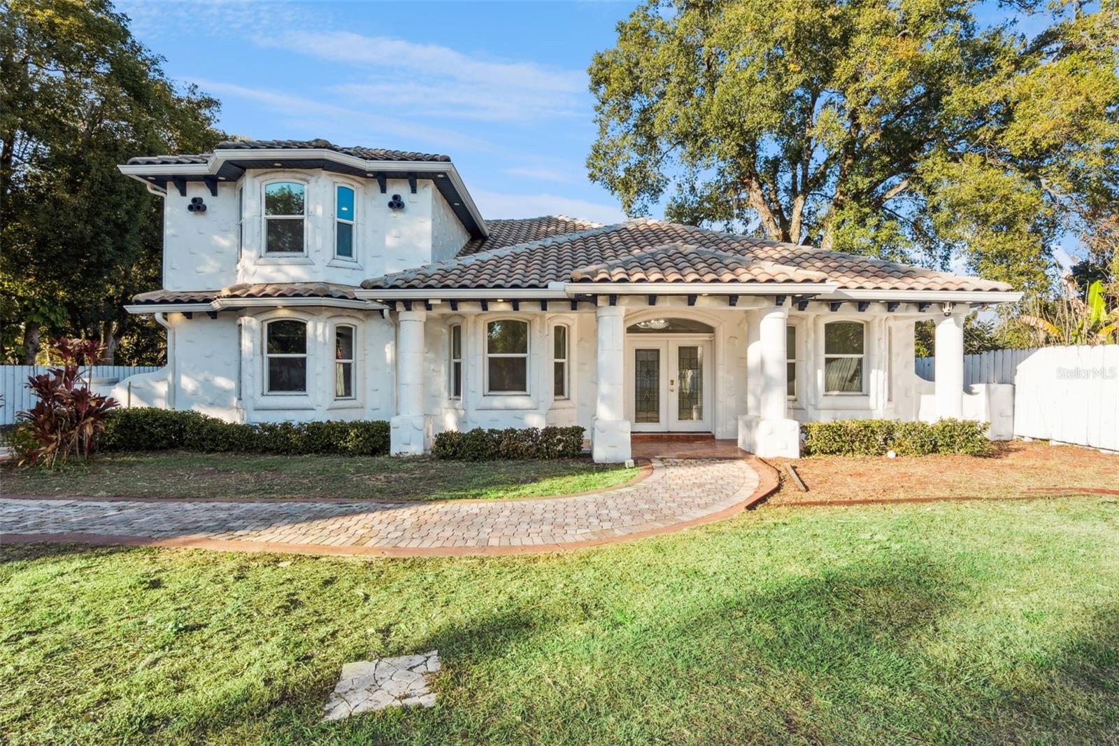 Step into elegance with this extraordinary Mediterranean-inspired estate, a custom-built two-story residence that effortlessly blends classic design with modern comfort. Set on an expansive 2/3-acre homesite with no HOA, this stunning 4-bedroom, 4-bath home offers exceptional privacy, space, and refined living. A grand gated entrance with a stately 9-foot wall leads to the beautifully maintained 3,784-square-foot residence, complete with a durable tile roof and a spacious three-car garage designed for convenience and storage.  The meticulously landscaped grounds feature a paver driveway with abundant parking, easily accommodating boats, RVs, trailers, and guests. Inside, architectural details abound, including soaring ceilings, crown molding, decorative columns, statement lighting, custom built-ins, and a wood-burning fireplace. The desirable split-bedroom floor plan enhances privacy, with three bedrooms offering en-suite bathrooms.  The primary suite is a true sanctuary, showcasing elegant tray ceilings, an impressive 35' x 12' walk-in closet, and a spa-inspired bathroom adorned with floor-to-ceiling travertine tile. The recently updated kitchen is both stylish and functional, featuring 42-inch cabinetry, quartz countertops, stainless steel appliances, double wall ovens, new flooring, and updated lighting—perfect for everyday living and entertaining alike.  The fourth bedroom, located on the second level, offers added flexibility with dual closets and its own dedicated central A/C system, making it ideal for guests, extended family, or a private office. Outdoor living is equally exceptional, with a spacious paver patio designed for entertaining, complete with a custom fire pit and fire bench that create a warm, inviting setting for year-round gatherings.  Ideally located just minutes from downtown Ocoee, Winter Garden, and Orlando, this home provides easy access to Highways 408, 429, and the Florida Turnpike. Enjoy nearby community events, farmers markets, dining, shopping, and Central Florida’s world-class attractions. Offering a rare combination of luxury, land, and location, this remarkable property is a standout opportunity in one of Ocoee’s most desirable areas. Schedule your private showing today to experience it firsthand.