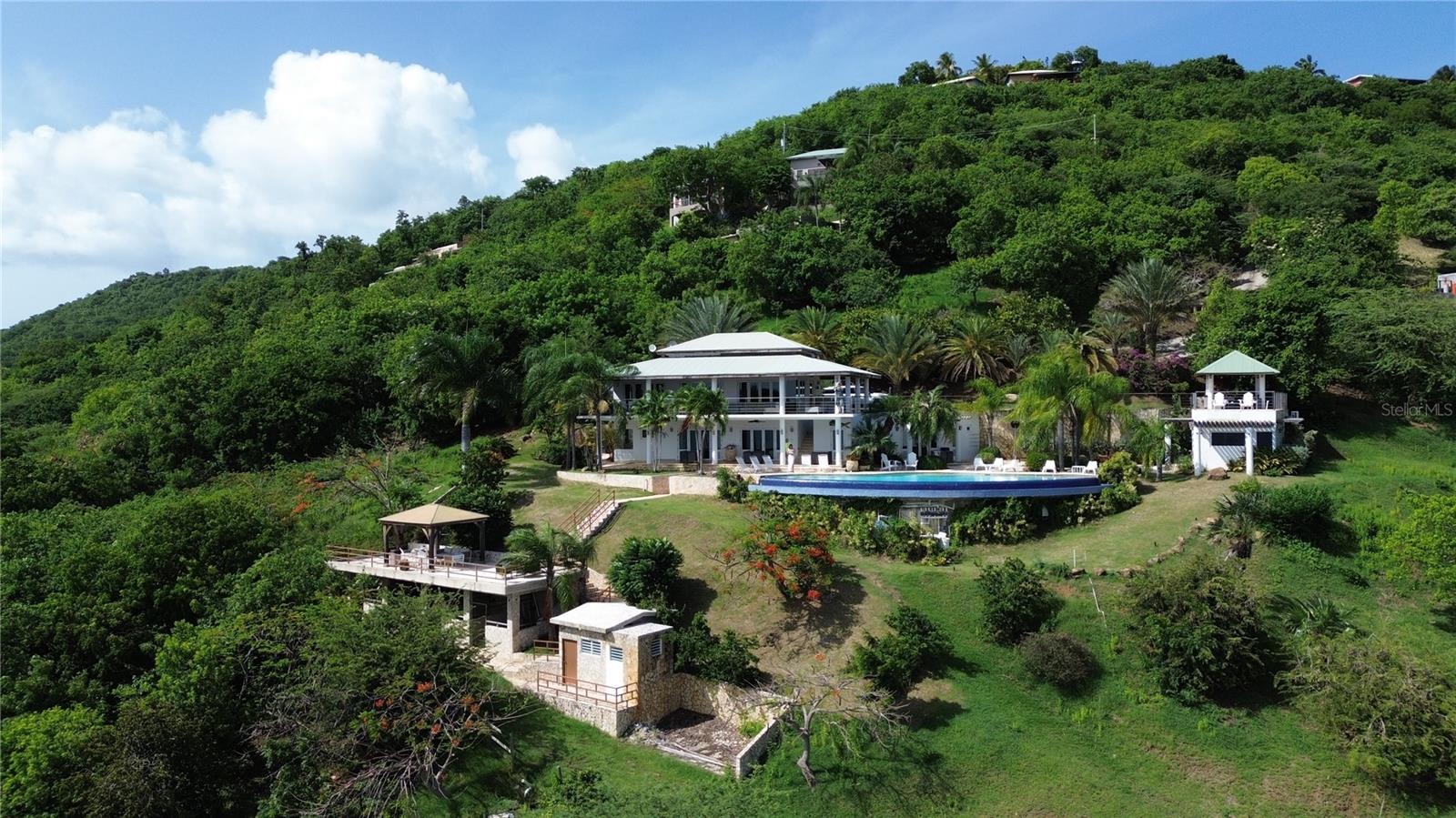 Let yourself be transported upon entry into this grand home located in Culebra, Puerto Rico, known for its crystal-clear waters, swimming areas, and diving sites. This sunny and spacious 5-bedroom, 6.5-bathroom home boasts ocean views from every room, as well as a terrace, balcony, and infinity pool! The stunning property is approximately a 10-minute walk to the beach and is very close to town and restaurants. The new horse stables have never been used and can be converted into a suite with a bathroom and kitchenette. The property is serviced by a septic tank and features AC in all rooms and living areas.

This is a two-level home with two separate gazebos. On the first floor (entrance), you'll find a fully equipped kitchen that seats up to 10, with two 33-bottle wine coolers and a double oven. Each room has its private entrance. The first floor includes 4 bedrooms, including 2 master suites: the first master suite has a king-size bed, TV, private bathroom, and chaise lounge. The second master bedroom has a king-size bed, mini fridge and microwave, private bathroom, and TV. The third bedroom features 2 bunk beds (each with a full-size bed on the bottom and a single bed on top, sleeping 6), TV, and a private bathroom. The fourth bedroom or studio has a queen-size bed, private bathroom, 2 sofas, and is adjacent to the living room with SAT/Dish and DVD player. Additional amenities include laundry facilities, an outdoor shower in the pool area, a lounge chair, large sofa, and a gas barbecue.