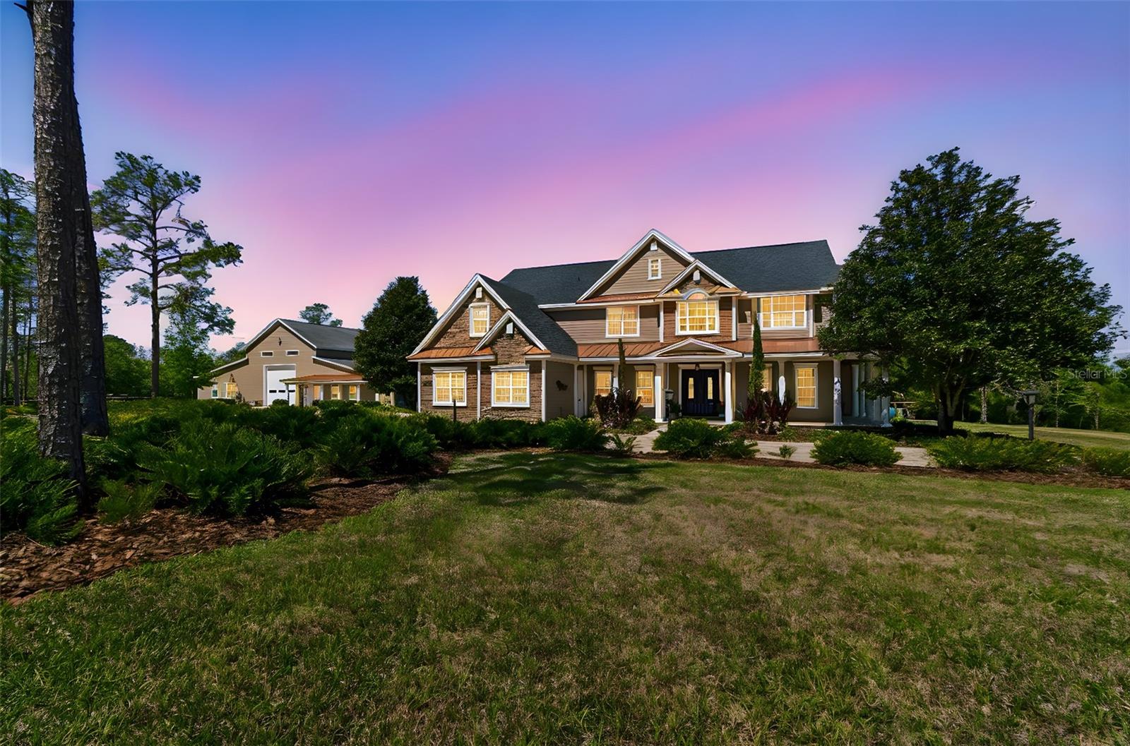 Tucked away at the end of a private paved road, this extraordinary estate offers luxury living surrounded by 21.7 acres of peaceful Florida countryside. Built in 2007 and meticulously maintained, the residence features 4 bedrooms, 4 bathrooms, a 3-car garage, and a resort-style pool, with a thoughtfully designed floor plan that blends comfort with elegant entertaining. The chef’s kitchen is equipped with high-end Viking and Miele appliances, including a gas cooktop, built-in coffee maker, and wine refrigerator, creating a space that is both functional and beautifully designed. The home also features a custom iron handrail along the staircase, adding to the craftsmanship and character of the interior.  Significant recent updates include a roof and all HVAC systems replaced within the past four years, providing peace of mind for the next owner.  The home is also equipped with a whole house generator.
Beyond the main residence, the property features an impressive 8,000 sq ft carriage house built to accommodate multiple motor coaches with drive-through capability, while also serving as an ideal space for a car collection, show cars, motorcycles, or large-scale entertaining. The building includes electric, water, multiple A/C units, a full bathroom, and its own septic system, along with a beautifully finished sitting room that could easily be converted into a private guest suite or mother-in-law quarters. A stunning custom bar and entertaining area make this an incredible space for gatherings, events, or multi-generational living.  A side-by-side utility vehicle and zero-turn mower are included and will convey with the property, offering added convenience for maintaining and enjoying the grounds.
The estate is further enhanced by a fully owned grid-tied solar system (no lease) that powers both the main home and carriage house, with current electric costs averaging approximately $40 per month, offering both efficiency and long-term savings.
This exceptional property offers a rare combination of luxury, privacy, and versatility, all within a convenient drive to major roadways, shopping, and dining. Properties of this caliber, offering substantial acreage, privacy, and extensive additional improvements, are rarely available. The property is ideal for RV or motor coach owners, car collectors, hobbyists, or those seeking a private family compound.