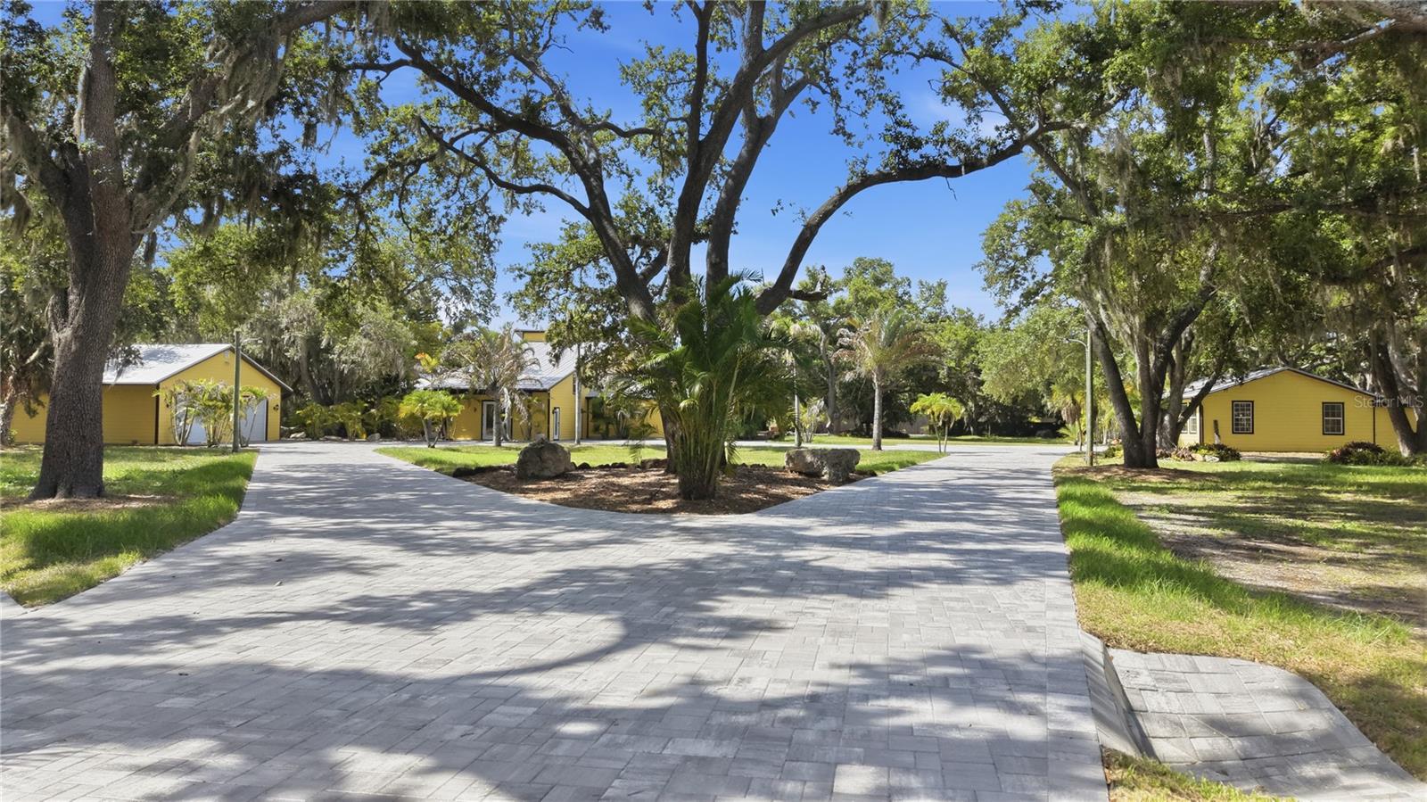 Fully Fenced and Gated 8 Acre estate in the heart of Sarasota. Over 8,000 sq ft of luxurious living space spanning across 8 majestic acres of landscaped park like beauty. This multigenerational property can accommodate the entire family in its 5 indoor kitchens, 1 outdoor kitchen, 3 SEPERATE houses with a total of 11 bedrooms and 9 bathrooms. Properties like this are truly rare for Sarasota. 
The professionally constructed main house with 2x6 fire rated walls spans over 5,800 sq ft. The main house offers 3 fully functions interior kitchens, 8 bedrooms, 6 bathrooms, 1 fully customized exterior kitchen situated under a Seminole built tiki hut with all the bells and whistles. The tiki hut is perfect for outdoor covered entertainment with a large bar that is wrapped in Bahia Blue granite, blaze appliances, dual sinks, 3 outdoor rated fridges, griddle, and a clear icemaker for those favorite cocktails. The main house has three separate private entrances each leading to your own spacious living space and own kitchen, ideal for multiple families with keeping the privacy if you desire. The grand piano room offers large windows for natural light, tall ceilings and a true gathering space for future family memories. There is a competition sized swimming pool that is 12' deep with sun shelves for lounging, a spa, and over 3,000 sq ft of marble deck space that stays cool even during summer. Exotic plants and boulders surround the pool for a real tropical vibe. Little ones and adults alike are able to work on their diving skills while the family watches from the lounging shelf. There are 2 SEPERATE DETACHED GUESTS HOUSES located on the property. A private 800 sq ft serene GUEST COTTAGE on the east side is tucked in the majestic oak trees and offers 1 bedroom/ 1 bathroom with a spacious living room, high ceilings and a front porch for taking in the views of the 100 year old oak trees lined along the creek. A SECOND 1,500 sq ft guest house on the west side of the property offers 2 bedrooms, 2 bathrooms and an extra den space for possible 3rd bedroom. In addition this 8 ACRE property features a brand new 15,00 sq ft paver driveway and a detached 3 car garage. This property has NO HOA, or deed restrictions and offers 2 GATED ENTRANCES. This is a multigenerational property that can be utilized in several different ways. Bring the whole family or use as rental income. The possibilities are endless with 11 BEDROOMS, 9 BATHROOMS AND 8 ACRES of pristine land only 10 minutes to downtown Sarasota. The location is ideal for shopping, beach going, boating and so many other lifestyles. Being only 10 minutes to hospitals, 20 minutes to St Armands circle and only 10 minutes to UTC Mall and I75. You can truly have it all. INVESTORS : This is a rare income opportunity for multiple streams of rental, totaling over 5 separate living units with 5 separate electrical meters all on county water and sewer.