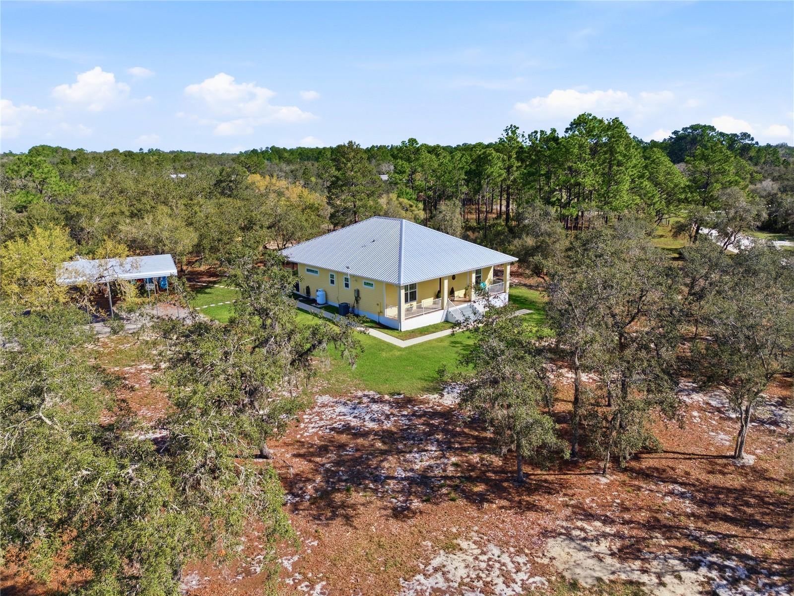 A True Escape Into Old Florida. Tucked deep within the (gated wildlife sanctuary) of Blue Jordan Forest, this remarkable (2.86-acre) corner property offers a lifestyle that feels worlds away from the noise, pressure, and pace of everyday life. Surrounded by protected land and untouched natural beauty, this is more than a home. It is a private retreat where peace, privacy, and nature take center stage. Set within a designated wildlife preserve, the setting is unforgettable. Bald (eagles) soar overhead, (deer) wander freely, and the sounds of cranes and native birds replace traffic and city noise. The (fully fenced) and gated homesite is carefully preserved with native scrub brush oaks and Georgia pines, creating a secluded atmosphere that feels both wild and welcoming. A private entrance and irrigation around the home add comfort and function while preserving the natural character of the land. Built in (2021), the custom residence was designed for durability, efficiency, and easy living. Construction includes concrete block filled with concrete and foam insulation, Hardie board siding, and a steel roof with spray foam insulation. The result is a home that is both strong and energy efficient, with electric costs averaging approximately $120 per month. Inside, the home offers an inviting open-concept design with 10-foot ceilings and tile flooring throughout, including the porches. The living spaces are comfortable, open, and easy to enjoy, whether you are hosting guests or simply savoring the quiet. The kitchen is beautifully appointed with granite countertops, custom cabinetry, a gas cooktop with stainless hood, double ovens, and Bosch stainless appliances. The primary suite is a peaceful hideaway with French doors to the screened porch, a spacious walk-in closet, and a well-finished bath with dual vanities and a walk-in shower. The guest bedroom is generously sized, also featuring a walk-in closet and easy access to a full bath. Outdoor living is where this property truly sets itself apart. The screened rear porch and custom outdoor cooking area with stainless hood vent, water connections, and Blackstone griddle create the perfect place to unwind, entertain, and fully take in the stillness of the surrounding preserve. Additional features include a (13kW) backup generator, (Starlink high-speed internet), underground utilities, a custom (8x20) utility building that matches the home, and a (20x24) steel carport with 14-foot clearance. Blue Jordan Forest is a rare, conservation-minded community of large acreage homesites, winding roads, and preserved landscapes. Life here is intentionally different. Ride ATVs or golf carts, plant a garden, explore the trails, and enjoy the kind of freedom and space that is becoming harder to find. Just beyond the gates, Frostproof offers a laid-back small-town setting between Lake Clinch and Lake Reedy. Nearby, the Lake Wales Ridge State Forest and Walk-In-The-Water Wildlife Management Area offer thousands of acres for hiking, camping, fishing, and exploring.
For the buyer craving privacy, quiet, and a place to truly disconnect, this property offers something rare in Florida: a genuine refuge from the world.