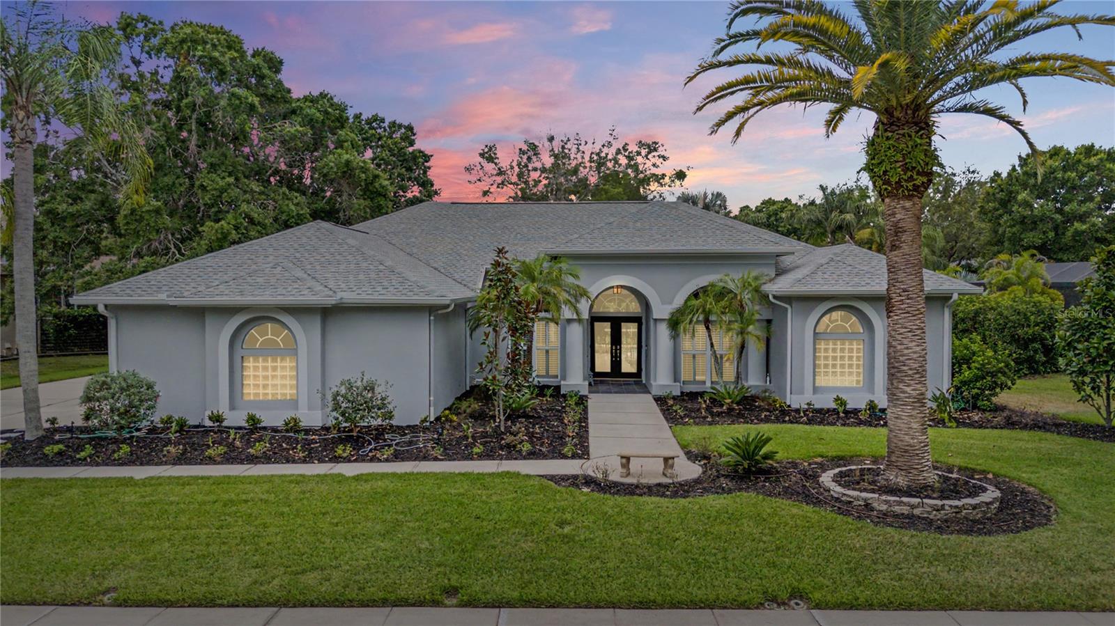 Welcome to a completely Reimagined Luxury in Lansbrook, an extraordinary estate nestled within the prestigious Juniper Bay enclave. Meticulously transformed from top to bottom, this stunning residence offers the perfect balance of luxury, comfort, and modern Florida living. From the moment you arrive, you'll notice the attention to detail that sets this home apart. Soaring ceilings, elegant architectural accents, and beautiful European oak flooring create a warm yet sophisticated atmosphere throughout. Designed with both everyday living and entertaining in mind, the thoughtfully crafted floor plan offers five spacious bedrooms, a dedicated office that can easily serve as a sixth bedroom, and multiple living spaces that flow effortlessly together. At the heart of the home, the chef-inspired kitchen is a true showpiece. Featuring premium appliances, quartz countertops, custom cabinetry, and expansive gathering spaces, it was designed for everything from quiet family breakfasts to memorable holiday celebrations. Large sliding glass doors blur the lines between indoors and out, opening to a spectacular screened lanai where Florida's year-round sunshine becomes part of everyday life. The owner's retreat serves as a private sanctuary, offering generous custom closets and a spa-inspired bath designed for relaxation and rejuvenation. Beautifully renovated guest bathrooms and thoughtfully positioned bedroom wings provide comfort and privacy for family members and visitors alike. Step outside and discover your own backyard oasis. The expansive covered lanai overlooks a sparkling pool surrounded by lush landscaping, mature trees, and carefully curated outdoor spaces that create a sense of peace and privacy rarely found. Whether hosting friends, enjoying family gatherings, or simply unwinding at the end of the day, this outdoor setting was designed to be enjoyed. Beyond its stunning appearance, this home offers the confidence of extensive improvements throughout, including updated plumbing, electrical systems, drainage, lighting, fixtures, and countless enhancements that elevate both form and function. Every detail has been carefully considered, resulting in a truly move-in-ready residence. Located within one of Palm Harbor's most sought-after communities, residents enjoy access to parks, walking trails, playgrounds, soccer fields, Lake Tarpon access, day docks, picnic pavilions, golf nearby, highly rated schools, and convenient proximity to Tampa Bay's finest shopping, dining, beaches, and airports. This is more than a home; it's a lifestyle defined by quality, elegance, and the memories waiting to be made. Opportunities like this are rare. Welcome home.