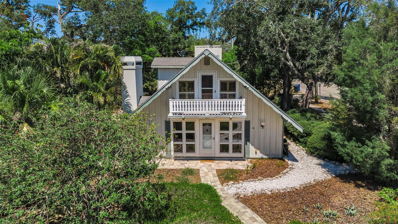 An absolutely charming home nestled on a fenced, corner lot is the perfect example of a rare and unique architectural nuance found in what is lovingly called “Delightful Dunedin”.  Amidst the natural beauty of this amenity-rich town, you’ll find this inviting 2-story/3 bedroom/2 bath with garage home. The sun-filled living room is spacious and boasts a dozen front-facing windows accompanied by a brick-faced, wood burning fireplace and hickory colored hardwood flooring. The adjacent dining room also reflects the natural light while the kitchen offers a rustic ambiance juxtaposed against stainless steel appliances, ample cabinetry, built-in spice rack, and generous pantry. The first-floor bedroom is wonderfully appointed with glass French doors revealing a private patio, making this space an ideal suite to accommodate a returning grad! Its accompanying bath features both a tub and shower, along with refined stylings. Upstairs, an expansive den can serve a multitude of purposes: playroom, home theater, or yoga studio with vaulted ceilings that lend drama to this exceptional space. Magnificent cathedral ceilings make a bold statement in the master suite crowned with skylights and made even homier with its own wood-burning fireplace flanked by more windows. The ensuite showcases a tiled shower room. The second upstairs bedroom is also light and bright with access to a lovely balcony overlooking the tranquil neighborhood. Beautiful pavers unify the large outdoor space and combine to create two individual pathways around the perimeter. A stone fire pit will be your new destination to relax and entertain. Besides a home security system, there’s a sprinkler system that uses reclaimed water. Additional room adjacent to the garage has A/C, perfect for work out room, office space, or an art studio complete with additional shower and a closet for storage. . A stunning waterfront town, Dunedin is known for the array of distinctive shops, eateries, and for hosting seasonal celebrations. Colonial Court’s cozy neighborhood is just minutes from Edgewater Drive Park on the Dunedin Channel, Dunedin Blue Jays’ stadium, Dunedin Fine Arts Center, and the Pinellas Trail -- the famous 47 mile venue that spans from Tarpon Springs to St. Pete welcoming joggers, skaters, cyclists, and anyone who wants to enjoy a scenic stroll!