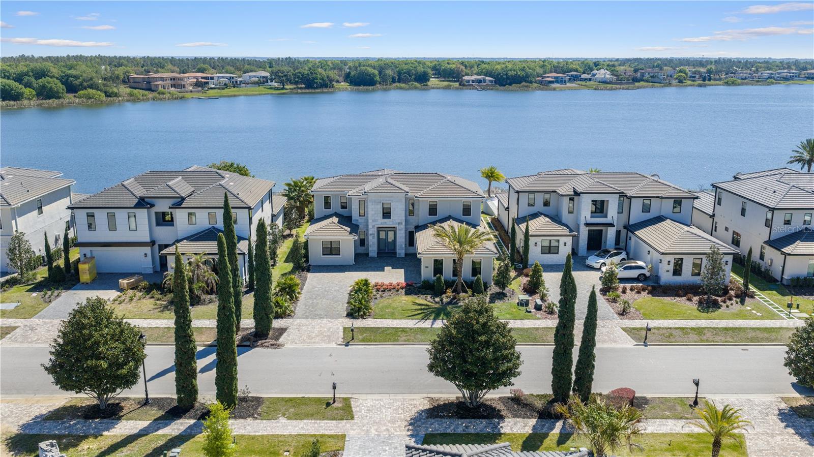This never-lived-in luxury residence presents an extraordinary opportunity to experience refined resort-style living within the prestigious guard-gated community of Bella Collina. Perfectly positioned along the shores of Lake Siena, this exceptional custom home offers 5 bedrooms, 4 full bathrooms, 1 half bath, and approximately 4,300 square feet of impeccably designed living space, all complemented by breathtaking panoramic lake views and unforgettable sunsets.
Designed to impress, the open-concept floor plan showcases soaring ceilings, and an abundance of natural light that perfectly frame the home’s spectacular water views from nearly every main living area. Elegant designer finishes and thoughtfully curated details create a sophisticated yet welcoming atmosphere throughout.
At the heart of the home, the gourmet chef’s kitchen is a true showpiece, featuring premium appliances, custom cabinetry, a dramatic waterfall island, gas cooktop with full ventilation, and seamless flow into the expansive great room and dining space — all overlooking the stunning lake views.
The luxurious primary suite serves as a private retreat, offering serene water views and a spa-inspired bath complete with a freestanding soaking tub, oversized walk-in shower, dual vanities, and spacious custom walk-in closets.
Additional highlights include a spacious bonus room, luxury flooring throughout, custom upgrades, and an insulated 3-car garage.
Step outside to experience resort-style outdoor living with a heated saltwater pool, covered lanai, WiFi-enabled pool system, and spectacular unobstructed views over Lake Siena, creating the perfect setting for both relaxation and entertaining.
Residents of Bella Collina enjoy world-class amenities including the Nick Faldo-designed championship golf course, resort-style pool, luxury spa, state-of-the-art fitness center, tennis and pickleball courts, fine dining, and an exclusive year-round social lifestyle. Conveniently located near Montverde Academy, upscale shopping, dining, and major highways, this residence embodies the very best of luxury living in Central Florida.