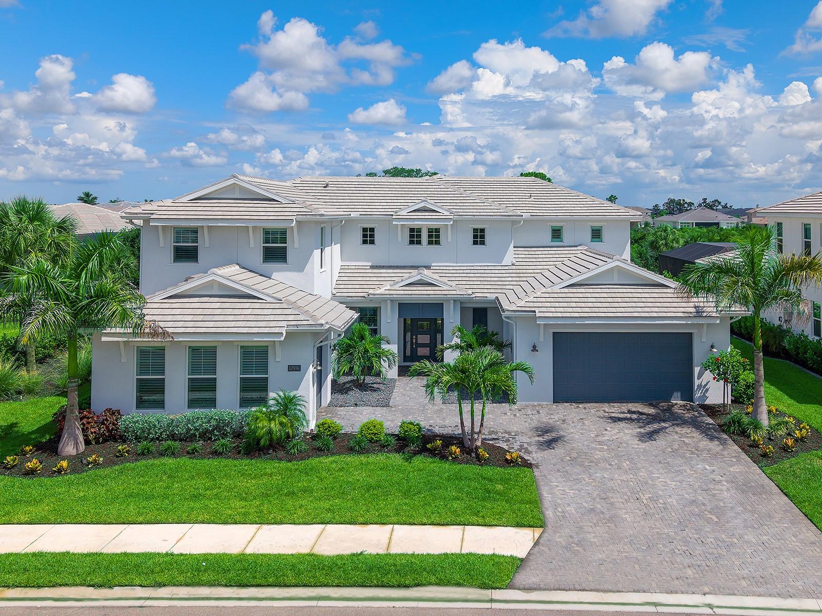 Designed for effortless luxury living and entertaining, this 2024 Toll Brothers Fullerton Caribbean residence offers 4 bedrooms, 5 full baths, 1 half bath, a dedicated office, spacious bonus room, and a split 3-car garage with separate 2-car and 1-car bays. A covered entry with a contemporary frosted glass front door opens to a dramatic 2-story foyer with engineered hardwood flooring and a striking staircase. Beyond, the great room features soaring coffered ceilings with exposed beams, designer lighting, a linear electric fireplace with a custom stone surround and wood mantel, and pocketing sliding glass doors that create a seamless connection to the lanai. Designed as the heart of the home, the gourmet kitchen is beautifully appointed with custom shaker cabinetry, glass-front display cabinets, quartz countertops, a full-height quartz backsplash, under-cabinet lighting, an oversized center island, expansive walk-in pantry and built-in desk area. A premium JennAir appliance package includes a 48-inch RISE built-in refrigerator, natural gas cooktop, vent hood, built-in wall oven, microwave and Noir dishwasher, while the adjacent dining area is enhanced by designer lighting, large plantation-shuttered windows and an open layout ideal for entertaining. Privately positioned on the main level, the expanded owner's suite offers a tray ceiling, spacious sitting area and 2 oversized custom walk-in closets with built-in organization systems. Its spa-inspired bath features dual quartz vanities, custom cabinetry, a freestanding soaking tub, oversized frameless shower with rainfall, handheld and standard shower heads, floor-to-ceiling tile, transom windows and a private water closet. Also on the main level are a private office with double-door entry, a beautifully appointed powder bath, a well-equipped laundry room with GE Profile washer and natural gas dryer, and a guest bedroom with engineered hardwood flooring, a walk-in closet and a private en-suite bath with a floor-to-ceiling tiled shower. Upstairs, the open catwalk overlooks the foyer and great room while leading to 2 guest bedroom suites, each featuring plantation shutters, designer finishes and private en-suite baths. The spacious bonus room with a closet and full bath provides exceptional flexibility as a media room, game room, or guest retreat. The resort-style outdoor living spaces are equally impressive with an expanded covered lanai, picture-frame screen enclosure, heated saltwater pool and spa with an auto-fill feature, textured marble pool decking, multiple covered entertaining areas and a fully equipped outdoor kitchen featuring a natural gas grill, vent hood, sink, refrigerator, tile backsplash and custom cabinetry. Built with concrete block construction and impact-rated windows and doors, this home also features a concrete tile roof, whole-house Generac 26kW generator, natural gas, a Rinnai tankless water heater, reverse osmosis system, dual-tank water softener, epoxy-coated garage flooring, professionally landscaped grounds with landscape lighting, smart home infrastructure and security and speaker pre-wiring. Located within the gated, maintenance-free community of The Isles at Lakewood Ranch, residents enjoy resort-style amenities including a clubhouse, fitness center, pool, spa, tennis, and pickleball. Located in the heart of Lakewood Ranch, you're minutes from Waterside Place, UTC, top-rated schools, dining, shopping and the Gulf Coast's renowned beaches.