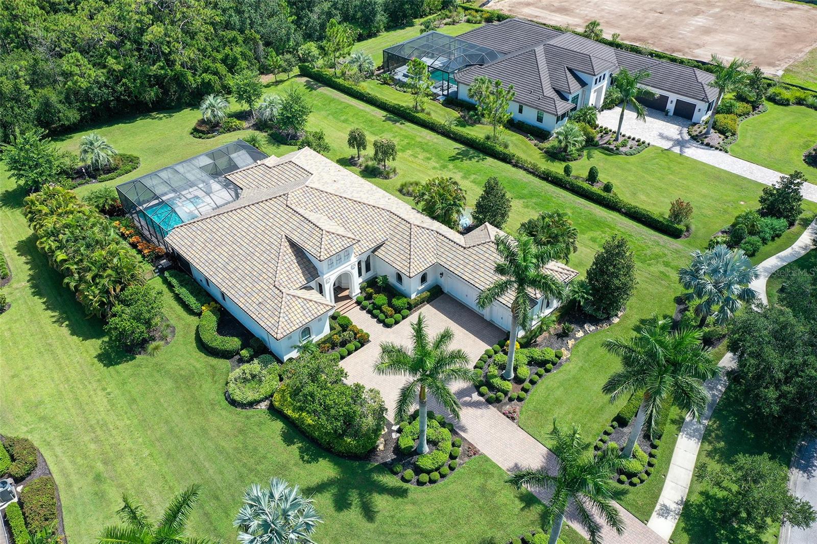 Set on a premier one-acre homesite in The Concession, 8361 Lindrick Lane captures the essence of refined Florida living. With tranquil lakefront sunsets at the front and a private preserve sanctuary at the rear, the orientation affords an unparalleled sense of serenity and seclusion. Its exceptional depth further distinguishes the property, offering the rare versatility to expand the residence or design a bespoke guest casita. The generous open plan blends elegance and comfort, showcasing 12-foot ceilings, wide-plank engineered flooring, and a striking stone feature wall with fireplace—elevating the home’s timeless sophistication. Designed for both daily living and memorable entertaining, the home offers three bedrooms, three full baths, a custom office filled with natural light, and a versatile bonus/media room. The chef’s kitchen is a centerpiece, featuring an impressive quartz island, natural gas cooking, built-in appliances, and seamless flow into the great room. Expansive pocketing sliders and a dramatic disappearing corner of glass open the interiors to the lanai, blurring the lines between indoor comfort and outdoor entertaining. The sweeping lanai serves as a private oasis, with a heated pool and spa, a fully equipped outdoor kitchen, multiple dining and lounge areas, and space for a fire pit beneath the stars. The primary suite is a luxurious retreat with French doors to the pool terrace, oversized walk-in closets, and a spa-inspired bath. A three-car garage and thoughtful finishes throughout further enhance this exceptional property. Constructed in 2015 and located outside of a high-risk flood zone, this residence offers both elegance and peace of mind. Renowned for its championship golf, available through optional membership, The Concession has hosted prestigious PGA Tour events including the 2021 World Golf Championships and the 2023 World Champions Cup, and will welcome the Senior PGA Championship this April. The club is complemented by celebrated wine-focused dining, world-class amenities, and serene natural beauty. Ideally positioned near Lakewood Ranch’s premier shopping and dining, and within easy reach of Sarasota’s finest Gulf Coast beaches, this residence offers an exceptional balance of exclusivity and connection.