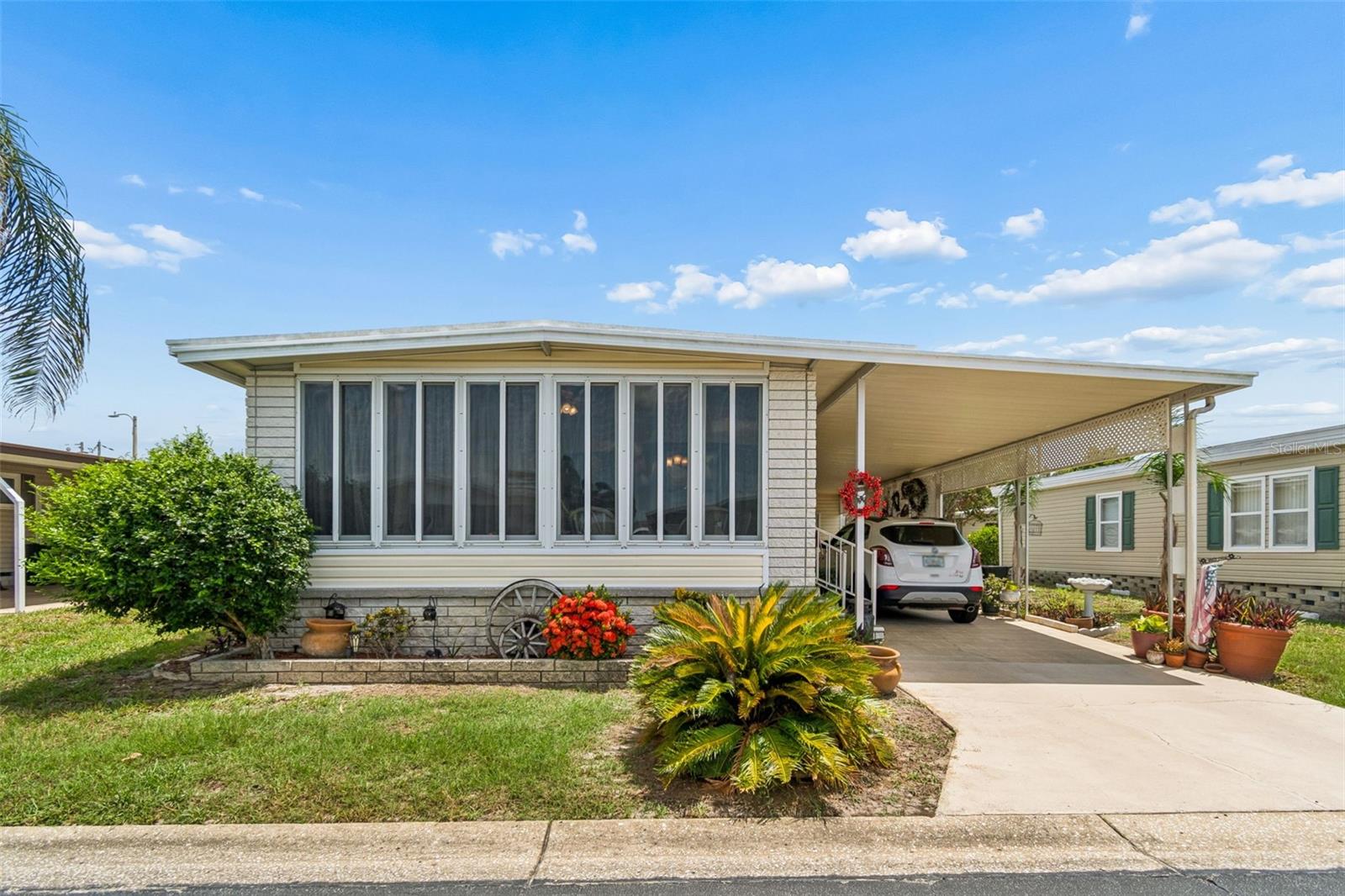 Welcome to your new home in the highly desirable 55+ resident-owned community of Glenwood Estates! This 2-bedroom, 2-bathroom home offers 1,152 sq. ft. of comfortable living. You will enjoy a seamless flow between the generous living room, formal dining area, and a central kitchen. A versatile flex space—currently styled as a cozy dinette—adds excellent functionality to the layout. Retreat to an impressive 200+ sq. ft. primary bedroom featuring an oversized walk-in closet and an en-suite bathroom with a dual vanity and a private, door-separated walk-in shower. Beautiful wood-look laminate floors flow seamlessly throughout the main living areas, complemented by durable tile in both bathrooms. Outside, relax on the charming front porch or enjoy the covered carport, which is currently configured with a cozy outdoor seating area that can easily be converted back to a second parking space. A sizable utility shed houses the washer and dryer, keeping your laundry convenient and out of your main living space. For an incredibly low monthly fee of just $260, almost all your utilities and maintenance are covered, including  trash removal, sewer, complete lawn care, and cable, high-speed internet, and Wi-Fi with equipment. Live like you are on vacation with top-tier community amenities, including beautifully manicured grounds with a peaceful lake, a heated swimming pool, shuffleboard, horseshoes, water aerobics, and a vibrant clubhouse packed with social activities. Take a virtual walkthrough from the comfort of your couch using the 3D interactive model, then schedule your private in-person tour!