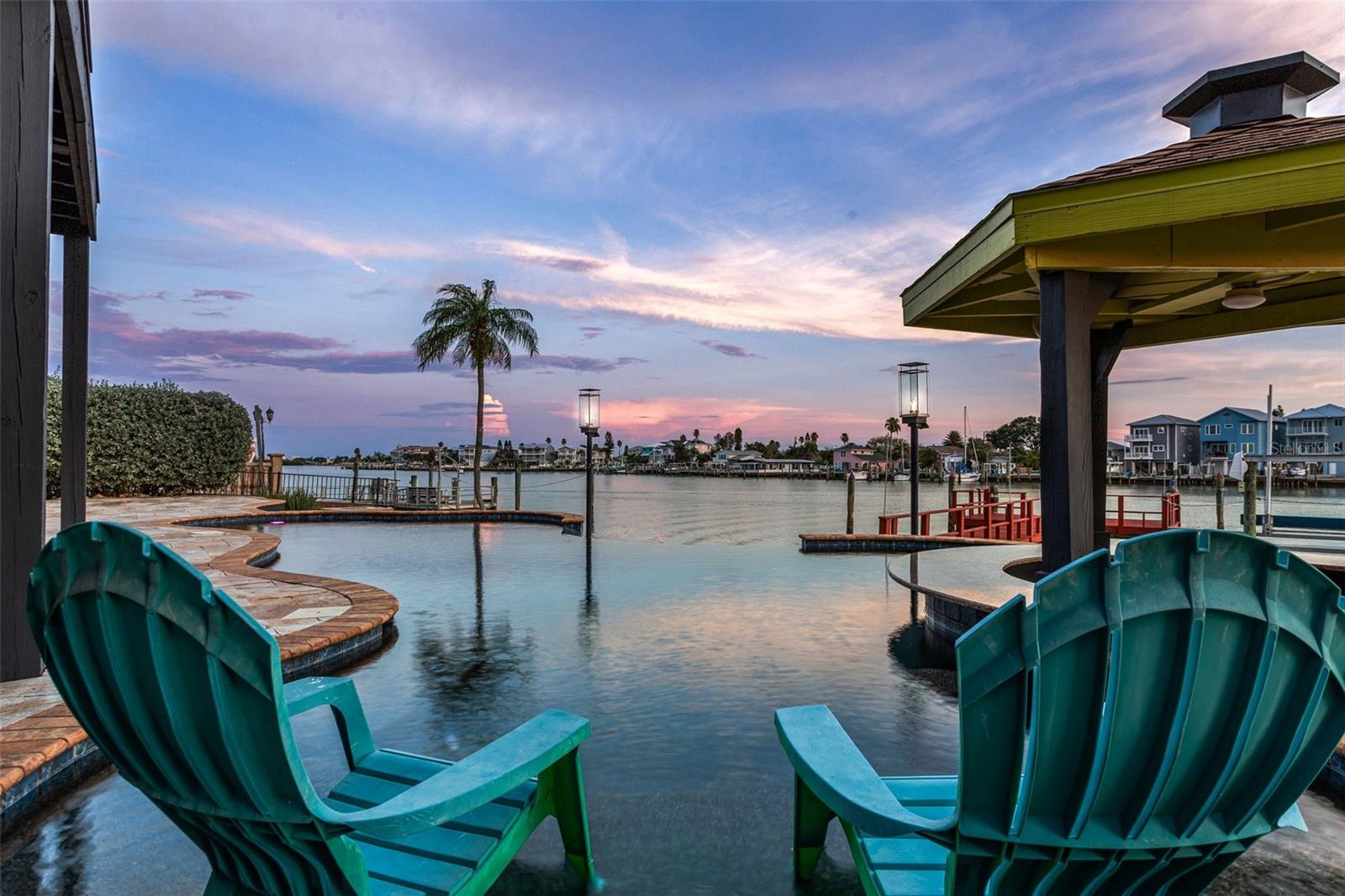 You are going to love coming home to this gorgeous WATERFRONT home on one of the widest parts of the intercoastal waterway, minutes away from John's Pass Village & the Gulf of Mexico.  This home is HIGH & DRY AND NEVER FLOODED and has 100' of water frontage on over a QUARTER ACRE lot! You will enjoy taking in the panoramic water view in the beautiful master suite overlooking all of the action or while enjoying a dip in the heated salt water INFINITY pool with a swim up tiki bar, so you can enjoy a cocktail while you take in the sunsets and watching dolphins swim in your backyard. You will be impressed by the ONLY Mid Century Modern beauty on Crystal Island with zero scape front and back yard featuring exotic cactus & succulent drought resistant gardens and brand new turf. Entering the house you will love the impressive foyer and entry way with beautiful Brazilian cherry wood and Travertine tile flooring throughout. Entertaining will be a breeze with a large, open living area transitioning to the dining room and kitchen with its own eat in area overlooking the pool and intercoastal waterway. As you step down to the family room you will be impressed with the gorgeous water views through the triple set of sliding doors with its own wet bar with wine and beverage coolers, ice maker and bar seating area as well as a beautiful gas burning fireplace! Invite family and friends over for a cook out in the expansive back yard where you can soak in the hot tub or take a dip in the heated pool with waterfall feature, a gas burning firepit and tiki torches! The master bedroom is where you will really love taking in the wide open views of the waterway with a giant separate en suite with programmable Hunter Douglas blinds or take in the fresh sea air on the large open second floor balcony. The HUGE owners bedroom also features another wet bar, mini fridge, his and her vanity sinks, a large walk in closet with built ins, a custom shower with multiple heads and zones, beautiful Brazilian cherry wood flooring and light fixtures. Both the second and third bedrooms are located on the second floor. Boaters and fishermen will love this home with its deep water GIANT dock with electric, fresh water and a large electric boat lift.  This home offers so much besides the locale and wonderful waterfront views like a BRAND NEW roof, GENERAC whole home generator, the largest SOLAR SYSTEM allowed in a residential property, 500 gallon underground propane tank, whole home water softener/filtration system, reverse osmosis system in kitchen, a separate office area on the upstairs landing, stainless steel appliances with a gas range, 2 HVAC units, two laundry closets and a laundry chute! If you ever have the desire to leave your beach oasis (why would you??), it's just minutes to all of the boating, fishing, swimming, shopping, dining, and nightlife that Pinellas county offers or if you feel more adventurous make the short drive across the bridge to Tampa where you can easily get to to I-75, the crosstown Expressway and I-4 so you can get to USF, MacDill AFB, Busch Gardens, Disney World, Universal Studios, or all of the wonderful Championship sporting events that Tampa has offer at Raymond James Stadium, Amalie Arena and Tropicana Field or spend the day boating or just relaxing on our world famous beaches.Make an appointment today for a private tour of this beautiful home before it's gone!