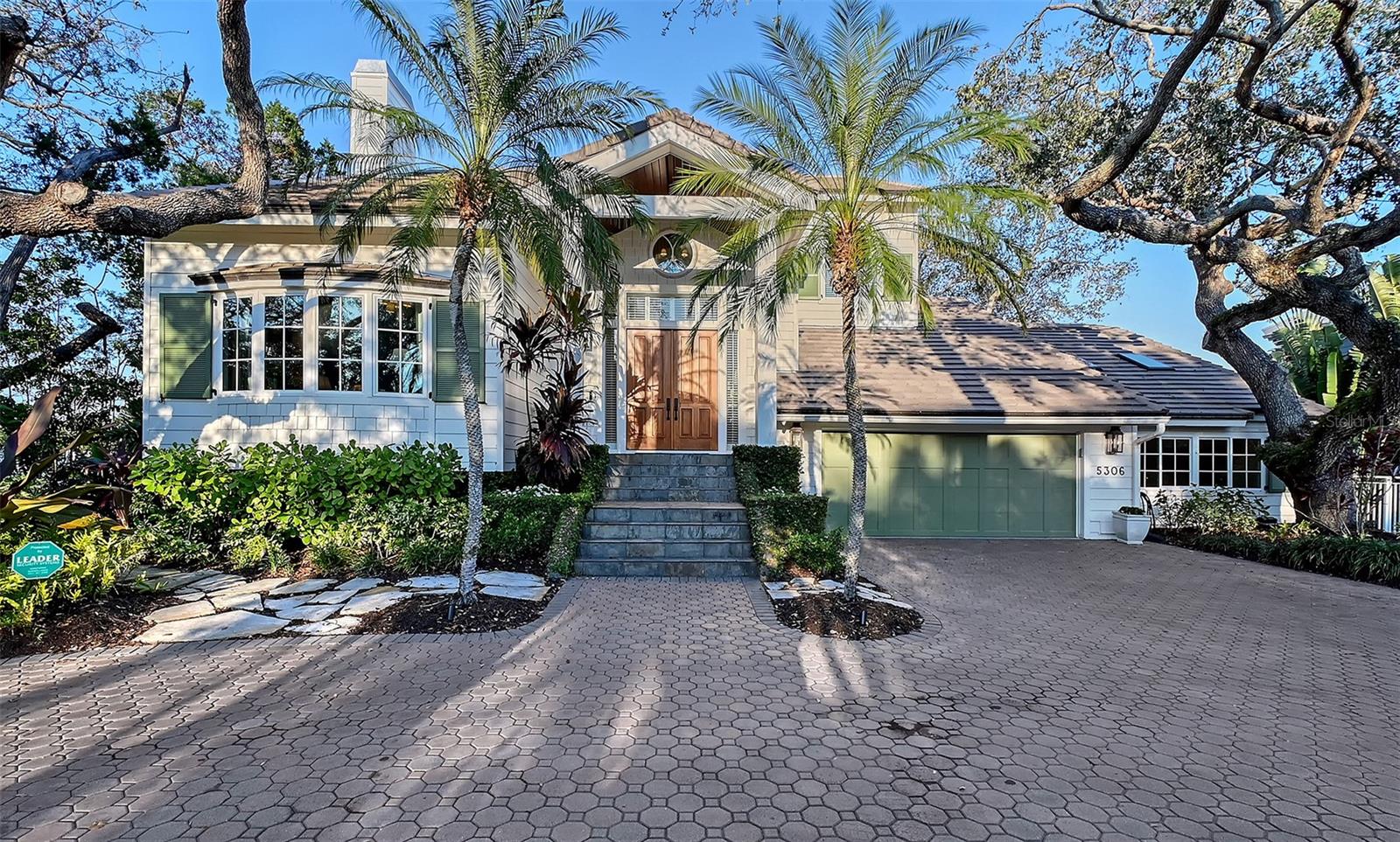 This elegant 5,000-square-foot waterfront home offers an exceptional blend of timeless style and modern functionality, with 4 en-suite bedrooms, 6 bathrooms, 2 home offices, 2 laundry rooms, and unmatched storage. A conforming home elevated to 10’ and recently remodeled (2023) with no detail overlooked, it exudes sophistication from the authentic copper lanterns outside to the finest-quality interior finishes. 

The exterior is updated with new impact-rated windows and skylights (2023), a new concrete tile roof (2023), and durable Hardie siding. A pavered circular drive, vine-covered slate steps, mature plantings, and dramatic landscape lighting create a welcoming approach, leading to 8’ solid mahogany doors that open to a stunning interior. 

Inside, generously scaled rooms with volume ceilings, detailed millwork, Duchateau French oak and imported French limestone floors, and a serene coastal palette set the tone. The semi-open floor plan ensures each space feels defined yet connected. From the grand three-story foyer, guests are greeted by a formal library with rift oak built-ins and a fireside living room. The adjoining dining room, complete with a French bistro-inspired wet bar and twin Subzero wine columns, comfortably seats twelve and opens to a covered Brazilian Ipe deck. A cozy family room with a built-in dining banquette and fireplace connects to an award-winning kitchen, featuring creamy inset cabinetry, honed Italian Calacatta marble counters, a solid walnut island, and luxury fixtures and hardware from Perrin & Rowe and Armac Martin. The tailored kitchen is equipped with a powerful, chef-grade Bluestar 60” gas range with a double griddle, concealed Miele fridge/freezer columns, and an Asko dishwasher. A highly functional scullery with an additional sink, an auxiliary 42” Subzero refrigerator, and a second Asko dishwasher complements the kitchen, while a walk-in pantry, in-wall chilled water dispenser, and secondary laundry center add convenience. A mudroom, a powder bath, and a full pool bath complete the main level. Down seven steps on the ground level, a vaulted bonus room offers a flexible space for a playroom, fitness studio, or hobby area. 

Up the foyer’s curved iron staircase, the second floor features three spacious en-suite bedrooms with water views, fitted closets, and an oversized laundry room with abundant storage and counter space. The third floor is devoted entirely to the primary suite, offering sweeping views of downtown Sarasota’s bayfront skyline. This luxurious retreat includes a private Ipe sundeck with spiral stair access to a rooftop deck, a second home office with built-ins, a spa-like marble bathroom with a soaking tub, two walk-in closets, and a versatile flex room ideal for a gym, nursery, or dressing area. 

Outdoors, 85 feet of deep sailboat water frontage provides a private escape with no homes across the way to disturb your view, only a lush mangrove island insulating you from Intracoastal Waterway boaters. The remodeled pool and spa (2021) are surrounded by stone pavers and premium turf, while a 60-foot Ipe dock with a 10,000-pound lift and illuminated pilings (2021) is perfect for boating enthusiasts. The home’s concrete stemwall foundation and elevated construction offer peace of mind, as do the four new elevated HVAC systems (2024) and two water heaters (2021/2024).