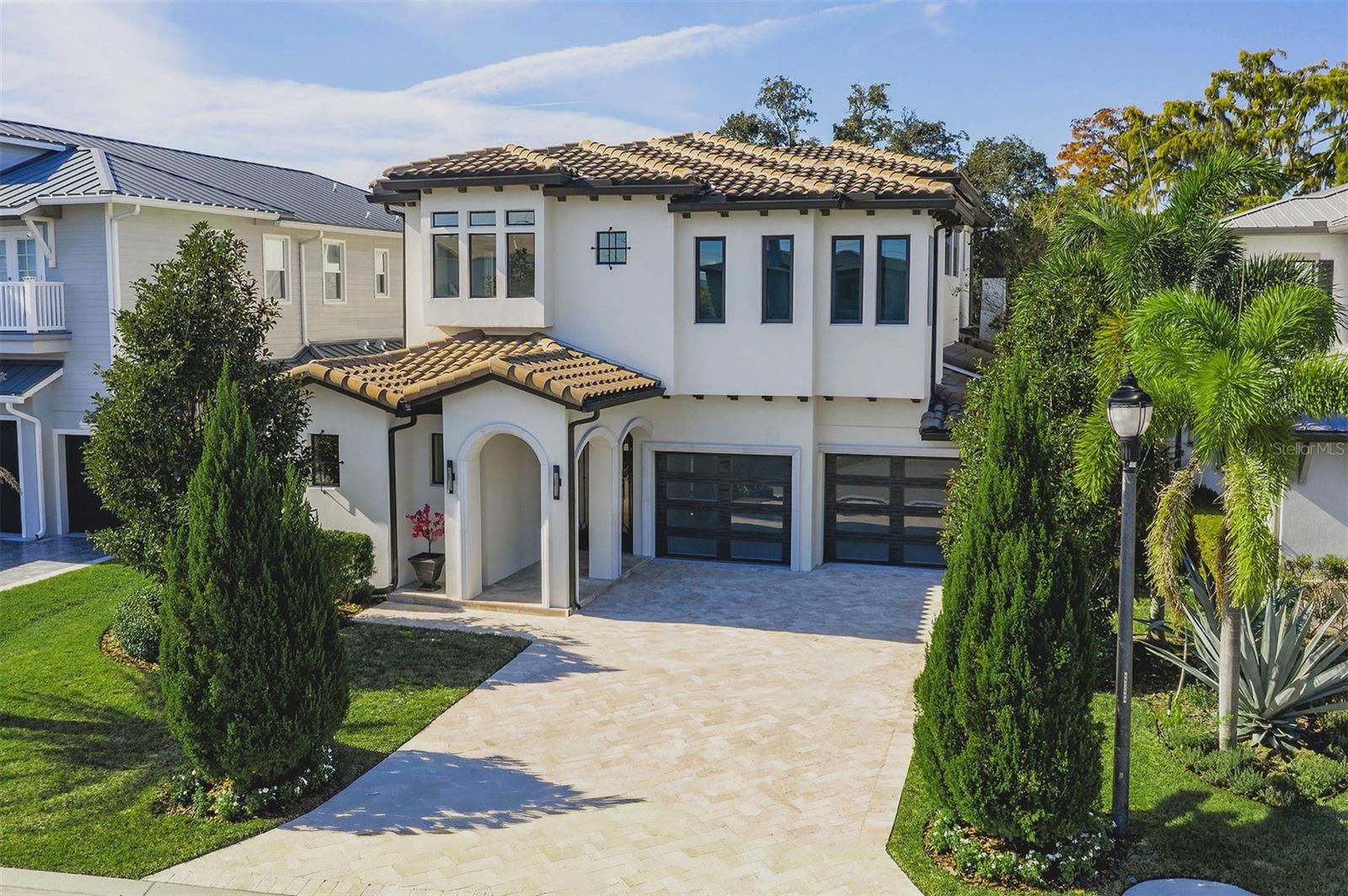 Completed in 2020, this exceptional Winter Park lakefront estate blends refined architecture, thoughtful design, and effortless indoor-outdoor living on Lake Killarney. Beyond the gated courtyard-style entrance, the main residence offers 5 bedrooms, 4 full baths, and 2 half baths, complemented by a detached in-law studio ideal for guests, extended family, or a private home office, with a full bath, walk-in closet, and a dry bar with a mini refrigerator. Behind the home, the rear lawn stretches down to the lake where an oversized boat dock provides  direct access to Lake Killarney for watersports or breathtaking sunset cruises. Enjoy a large deck, and an upgraded boat lift with 2 motors and a high-capacity cradle to accommodate a variety of boats. Throughout the home, a timeless neutral palette creates a warm and inviting space with modern elegance. An impressive open dining area greets you with soaring 2-story ceilings accented by exposed beams, and is adjoined to the kitchen by a well-appointed butler’s pantry for seamless hosting, complete with a dry bar and wine refrigerator, and a walk-in pantry. The kitchen is a true showpiece, with exceptional floor-to-ceiling cabinetry, 48” natural gas range with dual convection ovens, 2 dishwashers, and a built-in coffee/espresso machine. Anchoring the space, a large quartz-covered island offers 2 faucets plus a filtered water dispenser, and a butcher block prep space. The light-filled living room impresses with dramatic ceilings, a striking gas fireplace, and 10’ sliding glass doors that stack open to the covered lanai. A true extension of the home, the outdoor living experience is exceptional, featuring a summer kitchen, pool bath with an outdoor shower, and remote-controlled screens for year-round enjoyment. The resort-style pool and spa includes a sun shelf, all wrapped in travertine decking, overlooking the lake to provide a tranquil setting for relaxing with friends & family. Completing the main level is a private downstairs guest suite or home office, with a full bath and walk-in closet. Upstairs, the split-bedroom plan is separated by a versatile loft/bonus area with a dry bar and beverage fridge, ideal for a secondary living room, playroom, or study. Designed to embrace the home’s exceptional lakefront setting, the spacious primary retreat captures lake views through expansive glass doors, from the private balcony, and from the en-suite bath. The primary bath is luxurious, and thoughtfully designed to be a true sanctuary, with a freestanding soaking tub positioned to enjoy lake views, and a large glass-enclosed steam shower. Enjoy a very generous walk-in closet, with extensive built-ins and a center island that create a boutique-style dressing experience. The upper level also includes three additional bedrooms with wood floors, high ceilings, and easy access to 2 full bathrooms, plus a functional laundry room conveniently located off the bonus area. Perfectly positioned in Winter Park, with shopping, dining, and everyday conveniences just blocks away at the new and improved Winter Park Village, and the vibrant energy of the famed Park Avenue only minutes from your door, this lakefront home delivers the rare combination of newer construction and exceptional waterfront living—without compromise.