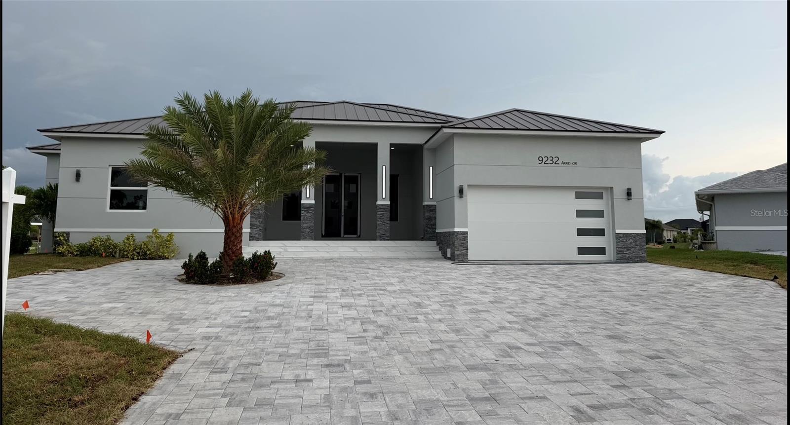 Finishing touches are being added. This extraordinary custom-built contemporary waterfront estate redefines luxury living in South Gulf Cove. Thoughtfully designed with over 3,400 square feet of sophisticated living space, every detail has been carefully curated to create the feeling of arriving at your own private five-star resort.
From the moment you ascend the grand entry framed by impressive stone columns and step through the dramatic 10-foot double doors, you're immediately captivated by breathtaking panoramic views of the sparkling pool, intersecting canals, and endless Florida skies. Walls of impact glass dissolve the line between indoors and out, filling the home with natural light and a sense of tranquility that instantly makes you exhale.

Imported 48-inch Italian porcelain tile flows seamlessly throughout the residence, while the expansive great room showcases a custom fireplace, built-in entertainment wall, art niches, and designer finishes that create an elegant yet welcoming atmosphere.

The gourmet kitchen is as beautiful as it is functional, featuring custom Egyptian wood cabinetry, premium stainless steel appliances, a stunning 10-foot quartz countertop island, all quartz counters,  abundant storage, and an adjoining butler's pantry complete with a full-size refrigerator, additional cabinetry, and quartz countertops—perfect for entertaining on any scale.
But the true heart of this home is the spectacular resort-style lanai. Designed for unforgettable gatherings, this expansive outdoor living space offers multiple areas for dining, relaxing, and celebrating life's biggest moments. The fully equipped summer kitchen with stone countertops and built-in grill overlooks the breathtaking convergence of two canals, creating an ever-changing waterfront backdrop. Whether hosting holiday dinners, watching grandchildren splash in the pool, enjoying sunset cocktails with friends, or simply savoring a quiet morning coffee, this outdoor oasis is where memories will be made for years to come.
As an added bonus, this coveted location offers front-row seats to South Gulf Cove's beloved Christmas Boat Parade, allowing you to entertain family and friends while enjoying one of the community's most cherished traditions from the comfort of your own backyard.
A beautifully landscaped paver walkway leads to the seawall and boat lift, making spontaneous days on the water effortless.
The luxurious primary suite is a peaceful waterfront retreat, offering private lanai access, tranquil water views, and an oversized custom walk-in closet with extensive built-ins. The spa-inspired ensuite is designed for total relaxation, featuring dual vanities, an elegant glass-enclosed wet room with a freestanding soaking tub, oversized shower with multiple shower heads, rain shower, built-in bench, and strategically placed windows that fill the space with natural light while creating the peaceful ambiance of a luxury spa. A private water closet also provides convenient access to the pool.
The thoughtfully designed floor plan offers spacious guest bedrooms w/individual ensuites. and beautifully appointed bathrooms, ensuring family and visitors enjoy both comfort and privacy.
This is far more than a home—it's a destination where weekends become vacations, holidays become traditions, and every sunset reminds you why you chose waterfront living. A truly one-of-a-kind opportunity in one of Southwest Florida's most desirable boating communities.