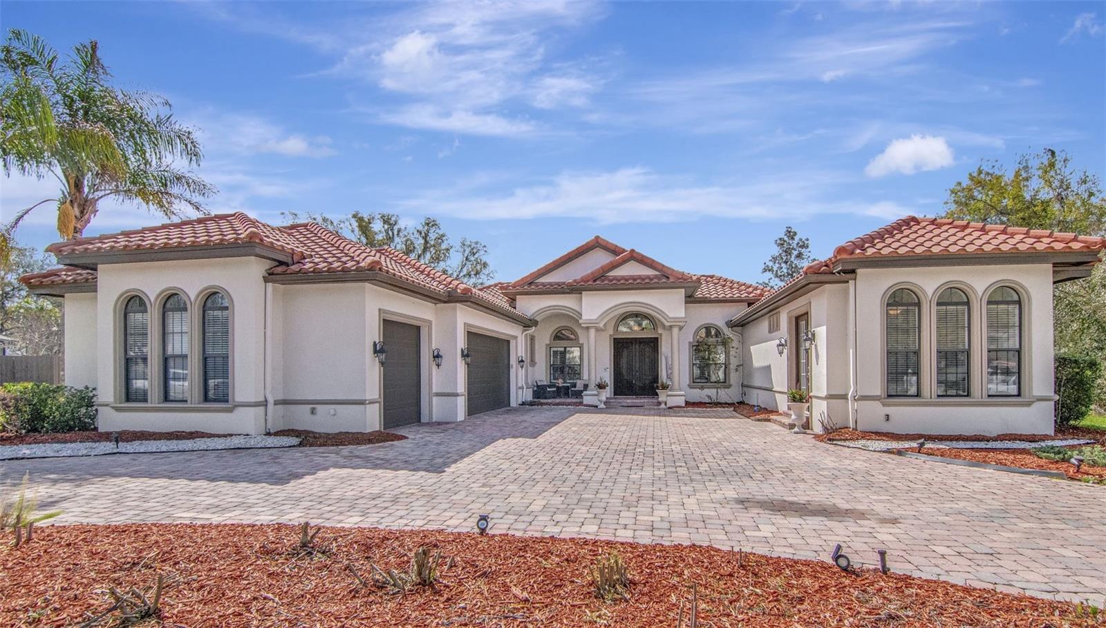 Rare opportunity to own a custom-built estate on a spacious .64-acre lot, featuring one of the home’s most valuable highlights — a private in-law suite with its own entrance. Perfect for multigenerational living, extended guests, or added privacy, this separate living space includes a kitchenette, full bathroom, and closet, offering comfort and independence rarely found in single-family homes.

The main residence lives as a 4 bed, 3 bath home all thoughtfully designed within a spacious single-story layout. From the moment you arrive, the home makes a statement with its stunning tile roof, half-circle paver driveway, and oversized 3-car garage, providing excellent curb appeal and plenty of parking.

Step through the grand double-door entry where your eyes are immediately drawn through the formal living area to the sparkling pool view beyond the expansive windows. Volume ceilings, plantation shutters, and all solid surface flooring add to the home’s elegant yet comfortable feel.

The primary suite, located privately on the right side of the home, is filled with natural light and offers tranquil views of the pool area. The suite features a tray ceiling with crown molding, two custom built walk-in closets, dual vanities, a makeup counter, a relaxing garden tub, and a large walk-in shower, all complemented by timeless creamy cabinetry.

To the left of the entry sits the formal dining room, featuring a beautiful built-in buffet that leads directly into the stately chef’s kitchen. Designed for both everyday living and entertaining, the kitchen features granite countertops, a center island with seating, real wood cabinetry with dovetail construction, glass-front cabinets, built-in ice maker, and a huge walk-in pantry. A large casual dining area sits beside the kitchen, all overlooking the spacious family room.

Just off the family room is a flex room perfect for a home office or den, along with a nearby full bathroom.

Down a separate hallway beyond the kitchen are two additional bedrooms connected by a Jack-and-Jill bathroom, along with a laundry room with built-in sink and cabinetry and convenient access to the oversized three-car garage.

French doors from the family room lead to a beautiful outdoor retreat featuring a heated pool with multicolor lighting and hot tub, surrounded by a large screened and fully pavered lanai. The fully fenced backyard offers privacy and plenty of space to enjoy the expansive lot.

Additional features include two brand-new AC systems (2026), a water softner and mature palm trees border the property.

Conveniently located near everything you need, the property is just 10 minutes to Advent Health, 12 minutes to HCA Hospital, and only 5 minutes to Publix grocery store, along with a variety of nearby shops, restaurants, and local plazas. Major roads and highways are also just a short drive away, making commuting simple and convenient.

This exceptional home combines space, privacy, and the rare advantage of a private in-law suite, all in a desirable and convenient location.