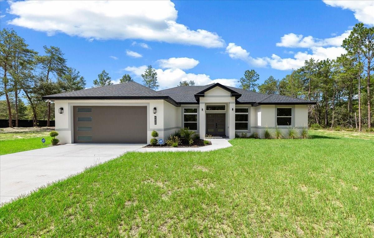 Experience the best of Florida living in this beautifully appointed new construction 4 bedroom, 3 bath home, set on a full acre in Marion Oaks with no HOA. Offering 2,053 square feet of thoughtfully designed living space, this home combines high-end finishes, modern functionality, and the privacy and flexibility that only a larger homesite can provide.  Everywhere you look, you’ll notice all the thoughtful touches that went into the design of this stunning home.  From the designer ceiling fans in every room, the upgraded lighting fixtures, the soaring ceiling in the main living area, to the large-format wood grain tile flooring, and 5.5-inch baseboards that extend throughout the entire home, no detail has been overlooked.  The elegant kitchen features custom 42-inch solid wood cabinets with under-cabinet lighting and soft close doors, quartz countertops that extend up as a full backsplash, and an oversized waterfall-edge quartz island with built-in cabinetry, a wine cooler, and recessed lighting underneath.  Nestled under a window overlooking the spacious backyard, you’ll find a fireclay farmhouse sink with a Kraus faucet, already wired for a garbage disposal.  Inside the multitude of cabinets you’ll find even more thoughtful touches, like a Lazy Susan tucked into a corner cabinet, a pull-out storage rack next to the stove, and a dedicated trash cabinet by the sink.  A stainless-steel appliance package rounds out the space beautifully.  
The private primary suite includes a tray ceiling with recessed lighting, a remote-controlled fan with light, a walk-in closet with a built-in shelving system, and a private entry door to the back patio. The en-suite bath offers a dual-sink quartz vanity, an LED lighted mirror with touch control and anti-fog capabilities, an oversized walk-in shower with frameless glass and a rainfall shower head, plus a private water closet, and a linen closet. 
There’s plenty of room in this home for family or guests, with 3 additional bedrooms, each one outfitted with recessed lighting and an upgraded fan with light and remote, plus two additional bathrooms, complete with quartz counters, touch-control mirrors and frameless glass showers.  
The outdoor living space is equally impressive. The expansive covered rear patio features epoxy-coated flooring, recessed lighting, two ceiling fans, and has plumbing and electrical already in place for a future summer kitchen. One bathroom opens directly to the patio, making it ideal as a future pool bath, and the spacious one-acre backyard offers ample room to design the pool and outdoor retreat you have been dreaming about.
And the upgrades don’t stop there:  additional features include a large laundry room with solid wood cabinetry, quartz countertops, and a utility sink; an oversized two-car garage with epoxy flooring, high ceilings, and a smart garage door opener with battery backup; impact-rated front entry doors; exterior dimmable LED soffit lighting with remote control, motion sensing flood lighting, and a full home security system for additional peace of mind.
Modern, spacious, and finished with exceptional attention to detail, this upscale Ocala home is the one you’ve been looking for.