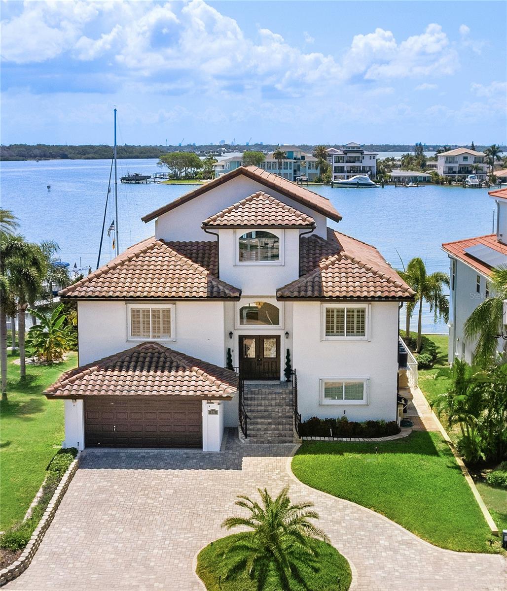 Welcome to this completely remodeled luxury residence in Madeira Beach. From the moment you step into the expansive great room, you are greeted by breathtaking open water views that epitomize the essence of waterfront living. Elevated on a sloped lot, this home represents the pinnacle of modern design, featuring soaring ceilings and custom, high-end finishes throughout. Everything in this home has been redone, ensuring a fresh and contemporary living experience.

This exquisite home boasts two master suites, including one conveniently located on the main floor. At the heart of the home is a custom kitchen, adorned with unique, exotic, leathered natural stone counters. These counters provide the organic look of marble while offering superior durability compared to granite, making them both beautiful and practical. With all new kitchen appliances installed in 2023, ample storage, and an eat-at counter.

The wide-open living areas are enhanced by luxury, wide oak, waterproof engineered wood flooring, adding elegance while ensuring durability and ease of maintenance. The home is equipped with a whole-house fire suppression sprinkler system and a Kohler power generator, ensuring peace of mind and uninterrupted living. Additionally, there are three newer air conditioning units and a high-end State brand water heater, providing efficient climate control and hot water.

With soaring 10 to 12-foot ceilings throughout, the home feels open and spacious. Custom plantation shutters on all windows allow control over natural light. The home also features hurricane impact windows and sliders, paired with an exterior hurricane shutter system for ultimate protection against the elements. A new swimming pool motor, enhances the functionality and enjoyment of the pool area.

A unique feature of this home is its extra wide seawall and additional double rebar-reinforced retaining walls, flanked by french drains, providing unparalleled structural integrity and safeguarding against the elements. The property also boasts a grandfathered 70-ft-long dock with not one but 2 lifts in sailboat deep water, offering exceptional waterfront access.

Its oversized balconies and covered patio are perfect for enjoying the serene waterfront views and entertaining guests. The home is strategically built on an elevated slope, offering enhanced protection. The over six-car garage area occupies less than half of the open lower level, providing ample space for vehicles while leaving plenty of bonus space for storage.

Nestled amongst exquisite custom homes of varying architecture, this exceptional estate boasts an unrivaled waterfront location next to an unbuildable park. Less than a mile walk brings you to the beach, coffee shops, and dining options, making it easy to enjoy the best of Madeira Beach. From the oversized dock, balconies, or covered patio, take in holiday boat parades, fireworks, and the serene sight of dolphins frolicking and boats cruising by in the no-wake zone.

This prime location also offers excellent accessibility to key destinations: it's approximately a 20-minute drive to downtown St. Petersburg,  and about 35 minutes to Tampa International Airport.