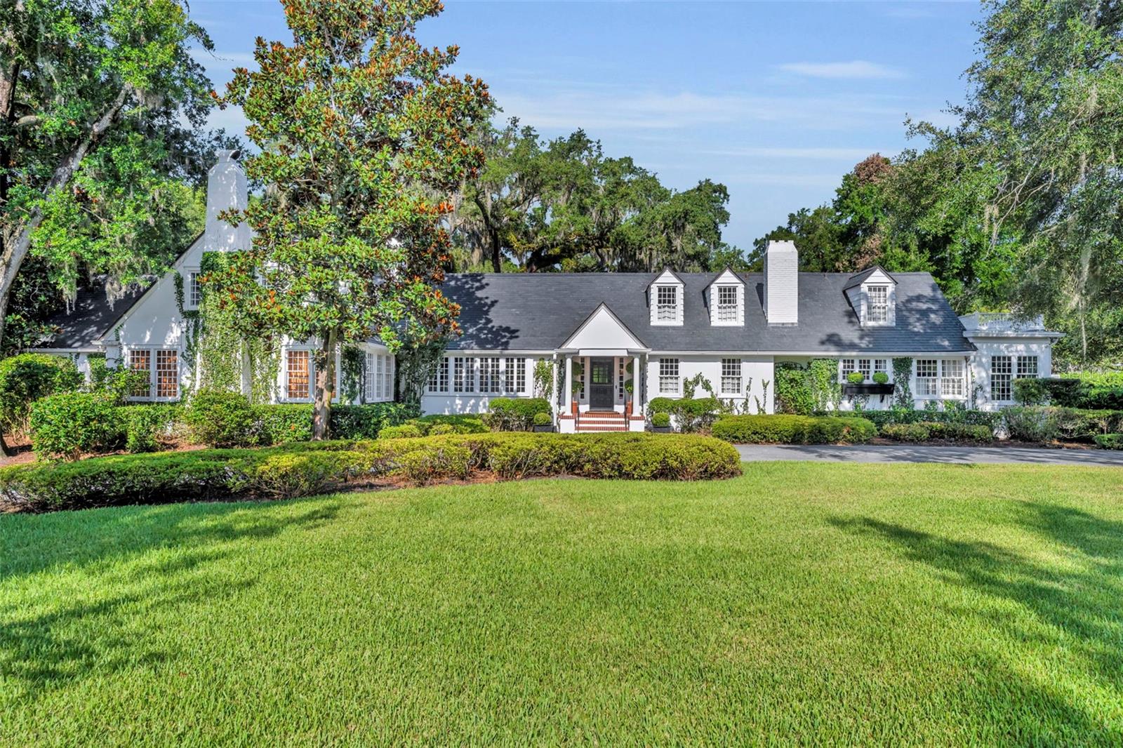 Offered for the first time in over 50 years, this distinguished Winter Park estate is a true traditional gem, nestled on a picturesque brick street and situated on a full 1-acre lot. Exuding timeless charm with a subtle New England ambiance, this residence represents the best of historic Winter Park living—all within walking distance to Park Avenue.
This stately 6-bedroom, 5.5-bathroom home offers 5,759 square feet of thoughtfully designed living space, plus an additional 1,859-square-foot unfinished basement that spans the entire length of the home, offering endless possibilities for expansion or customization.
Upon entry, you'll be welcomed by coffered ceilings in the spacious formal living room, rich dark oak floors, and one of the home’s three gas fireplaces. This elegant yet inviting room overlooks the lush gardens, making it an ideal setting for both entertaining and quiet relaxation.
Adjacent to the living room is a cozy, beautifully appointed den featuring another gas fireplace and natural jute flooring—undoubtedly one of the most beloved spaces in the home.
The kitchen is filled with natural light and includes a large casual dining area, a charming butler’s pantry, and direct access to both the laundry room—complete with a full-size refrigerator and half-bath—and the oversized 2-car garage.

The formal dining room showcases lattice-framed bay windows with views of the back garden and pool area, creating a warm and elegant space perfect for holiday dinners and family gatherings.
The home features two primary bedroom suites on the main level, including one expansive L-shaped suite with its own gas fireplace and views of the pool, gardens, and outdoor terrace. The primary bathroom includes a dressing area and marble finishes throughout.

Upstairs, the south wing includes two generous bedrooms with a shared full bathroom, while the north wing—located above the kitchen—offers two additional bedrooms and a charming full bath.

The expansive backyard is a private sanctuary, framed by majestic oak trees, bamboo, and thoughtfully designed gardens, with several inviting sitting areas for outdoor relaxation. An extra-large swimming pool completes the setting—perfect for warm Florida days or evening gatherings under the stars.