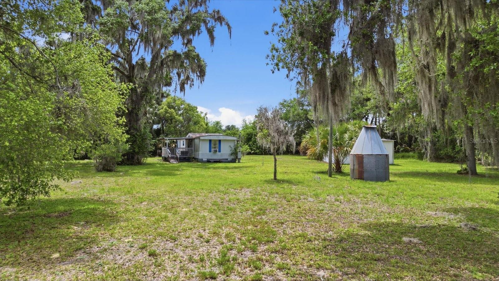 MAJOR PRICE IMPROVEMENT! Opportunities like this are becoming increasingly difficult to find. Situated on FOUR CONTIGUOUS LOTS totaling 4.9 private acres, this property offers a rare combination of acreage, privacy, existing infrastructure, and flexibility. Electric, well, septic, and paid impact fees are already in place, allowing a new owner to immediately enjoy the property and move forward with future plans without starting from scratch. Whether you’re looking for a private homestead, mini-farm, weekend retreat, investment opportunity, or future homesite, this property provides the space, infrastructure, and freedom to bring your vision to life. Surrounded by mature trees and natural Florida beauty, the setting offers exceptional privacy while remaining conveniently located to Crystal River, Lake Rousseau, the Withlacoochee River, and the Gulf. A 2-bedroom, 2-bath manufactured home currently sits on the property and provides immediate utility, but the standout feature of this offering is the nearly five acres of usable land, four separate lots, and existing improvements already in place. NO FLOOD ZONE. NO DEED RESTRICTIONS. Bring your horses, chickens, RVs, boats, and equipment. With a recent and significant price adjustment, this property deserves a fresh look from buyers seeking acreage, privacy, and opportunity. Properties offering nearly five acres with existing utilities and infrastructure already established are increasingly rare. Schedule your showing today and see the potential for yourself. Amazingly located just 12 minutes to The Lake Rousseau Dam & Recreational Area with boat ramp access to BOTH Lake Rousseau and The Withlacoochee River, which connects to The Gulf. Downtown Crystal River is about 20 minutes away for shopping, waterfront restaurants and Three Sister Springs/Hunter Springs Park for boating, fishing, beautiful nature walks & the only place to SWIM W/ THE MANATEES!