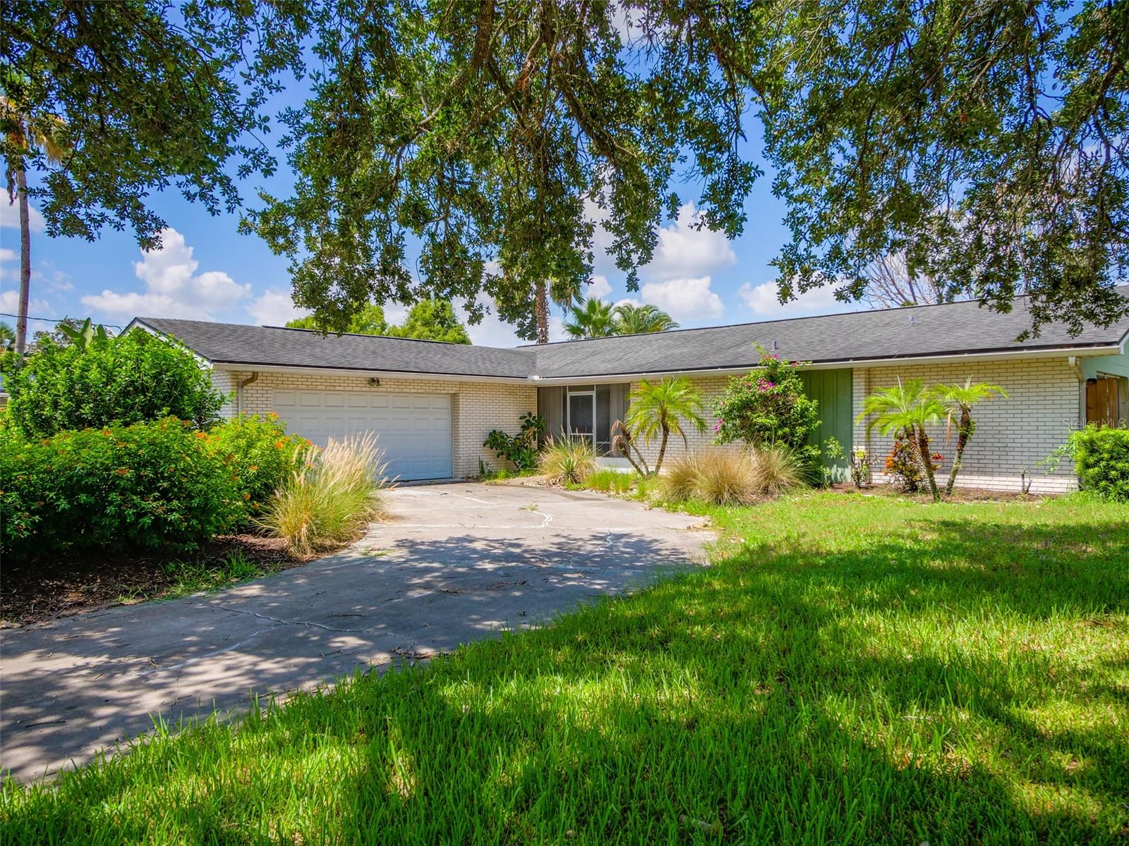 Virtually Staged. Welcome to this rare lakefront Mid-Century Ranch-style home in Dover Shores, just minutes from Downtown Orlando. This home is situated on a quiet dead-end street with lake frontage, a boat ramp, and an in-ground pool.  This 3 bedroom, 2 bathroom home offers character, space, and an incredible opportunity to create your dream home in one of Orlando’s most convenient locations.  From the moment you arrive, the garden-style front yard sets the tone with butterfly bushes and lush curb appeal. Step through the double entry doors into a Mid-Century-style foyer that opens into the main living room, where original details like the brick fireplace and wood panel features add warmth and architectural interest.  A built-in bar located by the sliding doors is perfect for entertaining and taking the party out back!  The sliding doors lead to an enclosed sunroom overlooking the backyard and a covered patio that connects the home to the pool and lakefront setting beyond. The bedrooms share a hallway, with two secondary bedrooms near a spacious hall bathroom. The primary suite is located along the back of the home and offers peaceful lake views and walk-in closet. This well cared for home shows permits for the roof in 2015 and electrical service upgrade in 2012.  Water heater is from 2019. Located near the 408 Expressway and minutes to Downtown Orlando or the airport. Zoned for Lake Como K-8 and Boone High School, this home offers a rare combination of lakefront living, Mid-Century charm, and everyday convenience. Truly special lakefront access this close to Downtown Orlando is hard to find!  Bring your vision and make this home your own.