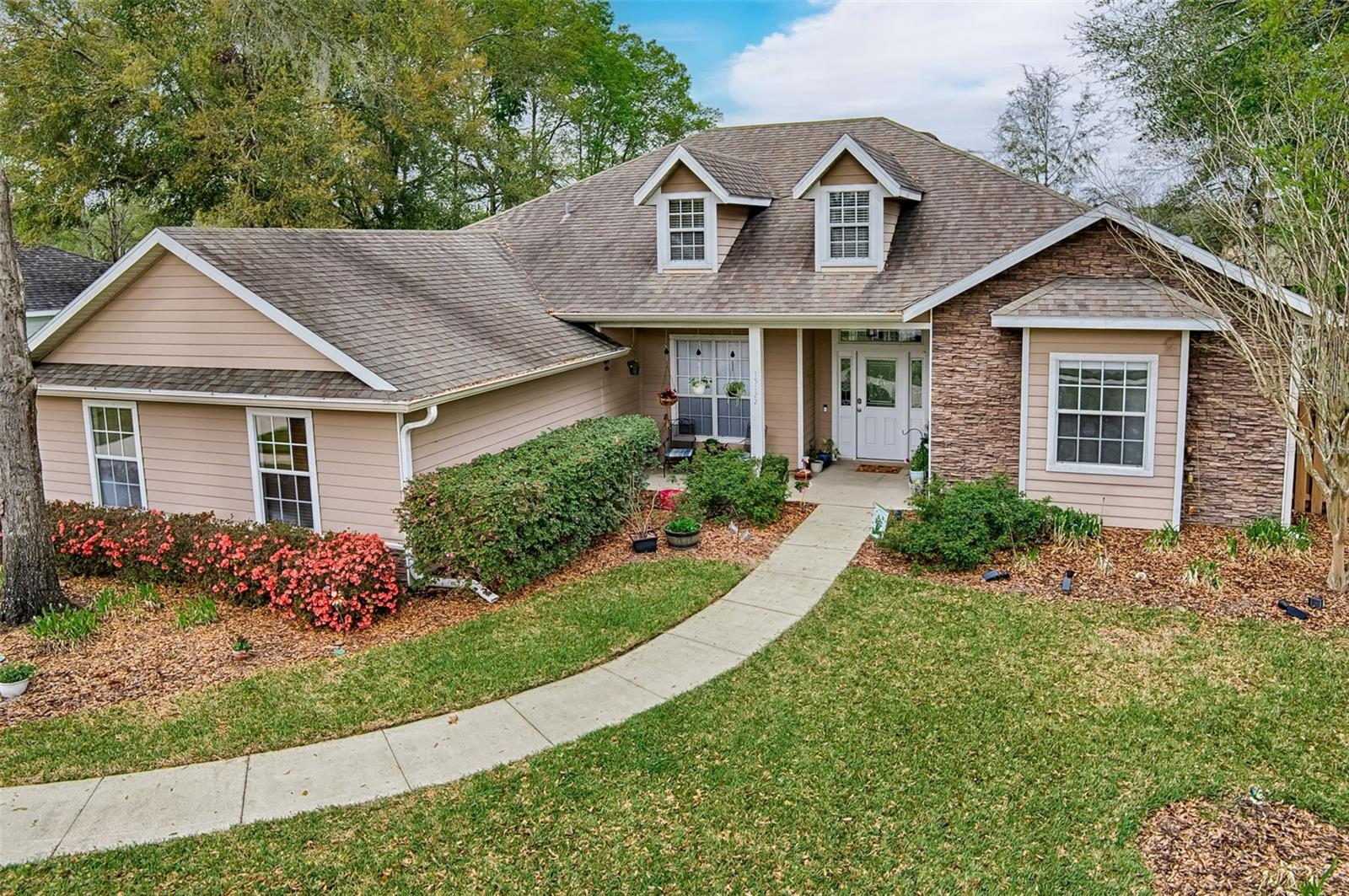 Tucked inside the gated community of Wyndswept Hills, this 4-bedroom, 3-bath home has a layout that works: whether for entertaining, families, working from home or all three at once. Step through the foyer into the living room anchored by custom built-ins and and tray ceiling, with sight lines straight through to the screened-in patio and a private backyard. The adjacent dining room carries the same energy, with engineered hardwood floors and its own tray ceiling detail. The kitchen is beautiful and functional: quartz countertops, stainless steel appliances, abundant cabinetry, a pendant-lit breakfast bar and breakfast room with backyard views. The primary suite has  a custom tray ceiling, a versatile sitting room (hello, home gym or private office) and direct patio access.  The en suite offers double vanities, a soaking tub, a glass-door shower and two walk-in closets. On the opposite wing, three additional bedrooms offer flexibility for guests, family or dedicated workspace. Two share a full bath; the third is a private en suite with its own walk-in shower, ideal for multigenerational living or a long-term guest. Out back, a full-length stone paver patio, raised garden beds and fruit trees create an outdoor space that's ready for summer evenings and weekend mornings alike. A large privacy fence keeps it all yours. Throughout the home: 10+ foot ceilings, engineered hardwood and vinyl plank flooring and a whole-house water filtration system. The laundry room with storage shelving and a utility sink connects directly to the garage. Ideally situated with quick access to I-75, US-441, and downtown Alachua's local shops and dining. UF, Shands, North Florida Regional, and the VA Hospital are all an easy drive away.