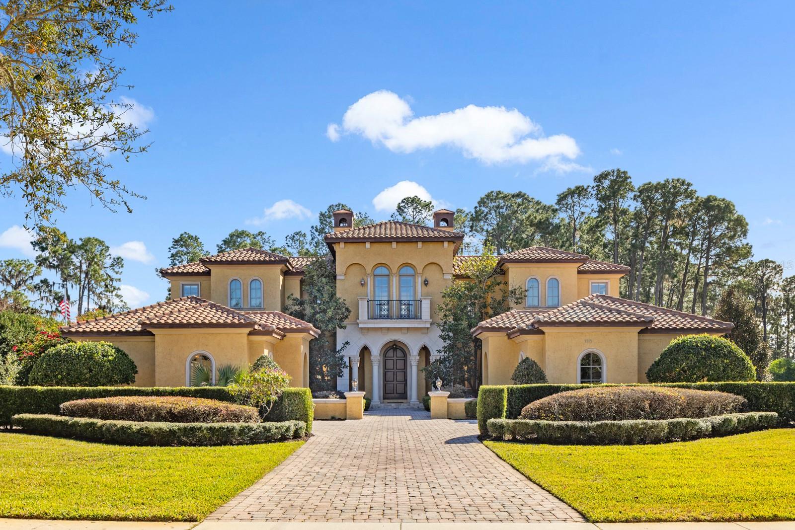 Windermere at its finest - elegantly appointed lakefront estate on the Butler chain in the gated country club community of Keene’s Pointe. Casa del Lago is a South-facing McNally custom home that has been expertly designed to allow the abundant natural light to accentuate its magnificent interior details while still offering privacy and astounding wooded and lake views over its almost 3-acre manicured grounds. Allow us to guide you through this lovely residence. 
Arrival: a stately driveway leads to twin motor courts and garage parking for 4 cars and a golf cart. 
Entry:  a solid wood 10-foot portico door welcomes you into an elegant travertine-tiled central two-story gathering area with clerestory windows overlooking the pool and lake and a tall stone fireplace; acoustics from the open circular music lounge above, also with lake views, allows this space to be grand while still intimate. 
Living: the East wing of the home opens into an expansive double island kitchen with custom wood cabinetry that masterfully houses the Wolf, Subzero and Miele appliances and the hammered copper farmhouse sink; the social heart of the home, it is accompanied by a pull-up kitchen bar and a delightful round breakfast nook with serving bar; it is adjoined on one side by the grand formal dining room (with walled courtyard) and flanked on the other by a cozy family room, all accented richly with hand-finished wood beams and woodworking details. Entertaining: leading off from the family room is the games room, ready for a full size pool table and card table and with its own pull-up bar, wine and beverage storage area, ice maker and separate media center; French doors open to the covered outdoor kitchen, dining and bar area with outdoor fireplace for the cooler nights and the large free-form pool, spa and deck; a 700-foot boardwalk leads to the lake where there is a dock with electric lifts for two jet skis and a boat, ready to explore the Butler chain of 13 lakes. 
Resting: the West wing is home to the elegant primary suite with indoor and outdoor sitting areas and dual luxurious bathrooms enjoined by a spacious dressing room with central island; there is one additional ensuite bedroom on the first floor and three more suites on the second floor which can be reached by stairs or the private elevator. 
Working/Studying: a large private office with walled flower-filled courtyard is located in the West Wing and there is a second office/homework room/hobby room on the second floor. 
Club Access: Keene’s Pointe is home to the Golden Bear Club whose members enjoy access to the 18- hole Jack Nicklaus golf course as well as restaurants, bar, tennis, club pool, fitness center and a full agenda of year-round family-friendly activities and events. 
All of this just minutes away from the charm of downtown Windermere and easy access to downtown Orlando’s best sporting and cultural events and the Orlando International Airport. Should you wish to expand the home or have more privacy, the vacant lot next door is also available (listed and priced separately). Your Casa del Lago awaits!