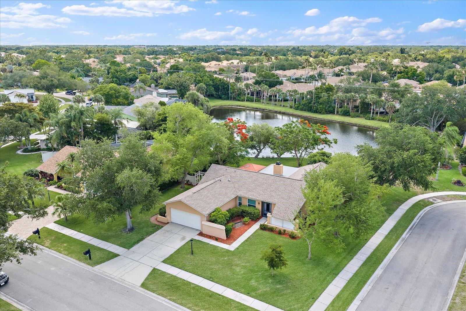 Positioned on an oversized cul-de-sac corner lot overlooking a lakefront backdrop, this updated 3-bedroom, 2-bathroom Sarasota residence offers a combination of water views, functional living spaces, and meaningful improvements throughout. Mature landscaping, expansive green space, and a waterfront setting create an inviting backdrop, while the home's thoughtful updates provide move-in-ready convenience.
Inside, vaulted ceilings and an open layout create a bright and welcoming atmosphere. The kitchen has been updated with solid wood soft-close cabinetry and drawers, granite countertops, stainless steel appliances, a decorative tile backsplash, and a large center island that provides additional workspace, storage, and seating. A brand-new refrigerator and newly painted interior further enhance the home's updated appeal. The split-bedroom floor plan provides separation between the primary suite and guest bedrooms. The primary bathroom features updated cabinetry, granite countertops, and a walk-in tiled shower, while the guest bathroom has also been updated. Multiple living and gathering spaces, including a spacious family room and separate living room, offer flexibility for a variety of uses. Designed to maximize the lakefront setting, the enclosed Florida room provides panoramic water views and serves as an extension of the living space. Outdoors, a custom pergola, paver patio, fire pit area, and lakeside seating spaces create multiple opportunities to enjoy the backyard and waterfront surroundings. Mature trees frame the lake views and contribute to the property's distinctive outdoor setting. Additional improvements include a brand-new roof, custom front entry door, attic fan, updated interior finishes, and an attached two-car garage. Conveniently located 10 minutes from the beach & near shopping, dining, recreational amenities, and major transportation routes, this property combines a desirable lakefront location with significant updates and versatile living spaces.