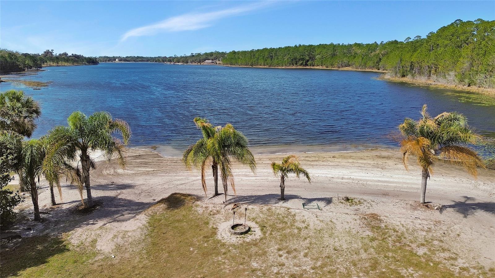 Welcome to one of Volusia Counties Most Pristine Lakes. Lake Winona and its Crystal-Clear Waters offer all that Lake Front Living can. Enjoy waterskiing, fishing, boating, sailing, paddle boarding and Amazing Sunsets. Lake Winona has long been recognized as a magnificent water ski lake. This Amazing offering features an updated 1934 home on 5 +/- acres with approximately 290 feet of waterfront living. The living room features include a brick fireplace, hearth and beautiful wood floors. The classic kitchen and the dining room have awesome views through the windows of the magnificent Live Oak offering shade on the summer days. Through a door off of the dining room, you will be amazed with the cozy Pub like feeling with the cool stone fireplace and sitting area, then step outside and relax on the wood deck. The Primary Bedroom has wood floors. The main bathroom has been updated with a nice tile shower. Oversized laundry room features a half bath and storage with door to the outside. The exterior of the home has been recently painted; the roof was replaced in August of 2023. That is just the beginning of what this property has to offer. There is a Magnolia Tree grove, several Fruit Trees, lots of room for a garden, a basketball court just to start. The barn has an amazing Mother-In-Law, 1 bedroom / 1 bath (shower), kitchen and living room or it can be a really nice guest house for visiting family and friends. The barn has lots of workspace, ample electric, a refrigerator and storage for the equipment to care for the property. As you continue toward the lake you will find the Gazebo for enjoying the lake view. The best part of this property is the white sand beach, enjoy swimming while relaxing by the lake. The location is off State Hwy 11 which makes access to Daytona Beach, The Worlds Most Famous Beach, Daytona International Speedway. Less than an hour drive to Orlando and the Attractions.