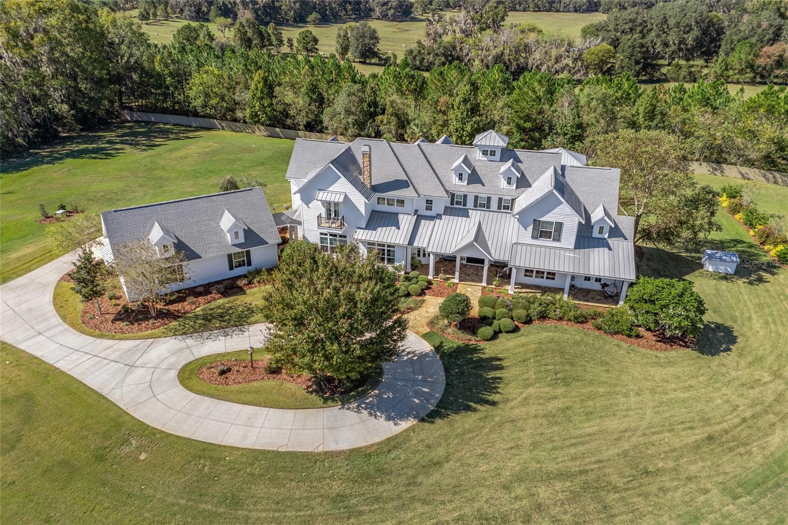 Welcome home to Estate Living at its Finest! This custom-built hidden gem boasts 5 bedrooms / 5.5 bathrooms with over 6900 square feet of living area, overlooks a 9-acre spring-fed pond, and sits on over 38 areas of meticulously kept grounds with rolling hills throughout. Entering the home your met with the great room showcased with patterned wood beam ceiling, wood burning stone fireplace flanked by French doors leading to the covered patio and open concept cabinets which provide a subtle separation to the other living areas. Rich brown-toned natural hardwood floors throughout the main floor blend each of the living areas seamlessly. The chef’s style kitchen features wood cream-colored cabinets with matching panel fronts for the fridge and range hood, granite countertops, Thermador Professional appliances include 6 burner gas stovetop, built-in double oven, warming drawer, fridge, 2 dishwashers and microwave. The functional island offers sink, storage, multiple serving areas and additional seating. Additionally, there is a large glass front cabinet with plate rack to display your special items, a second sink with pass-thru to El Fresco dining area with Travertine tile and separate large walk-in butler’s pantry. Two separate dining areas which both provide easy transitions to the kitchen and living areas. A secondary living area overlooks the front of the property and pond and highlighted by stone wood burning fireplace, creating a cozy comfy atmosphere. Primary bedroom located on first floor has private entrance with double doors, large bedroom with trey ceiling and French Doors overlooking the pond, 2 large walk-in closets with built-in dressers and open clothing cabinets. The en-suite primary bathroom is adorned with 2 separate vanity areas, oversized walk-in shower with bench, water closet and direct access to private outdoor shower. Completing the first floor is the office with double glass doors, gym, wine cellar with wine fridge, elevator and a robust laundry room with concrete counters, cabinets, sink, open office area and access to outside patio area, half bath with attached mudroom drop zone for pool. Second floor hosts 4 bedrooms and bathrooms all with walk-in closets (3 bdrms are en-suites), an open bonus room with kitchenette, hide-away office and multiple storage rooms and closets. Stepping outside to your backyard oasis you’ll discover the covered patio with Travertine tile, enhanced with pass-thru bar area with additional seating, fiberglass saltwater pool with sundeck, cabana with plank ceiling and lounging deck. The 8-stall equestrian barn is showcased with center-aisle, inside wash area, office and tack room, awnings for each stall window and caretaker apartment which is plumbed and ready for build-out. Outside wash rack, garden, 5 fully fenced pastures 3 with run-in buildings, well and septic and equipment garage. The 9-acre pond brings nature to you and creates a moat-like entrance after passing through the gate with 2 bridges to gain access to the home. Fish, relax or board your vessel for a trip around the pond from the covered dock and pier. 3 car rear facing garage with attic pull-down for additional storage, property is perimeter fenced, front porch and walk paths are Tennessee Flagstone.