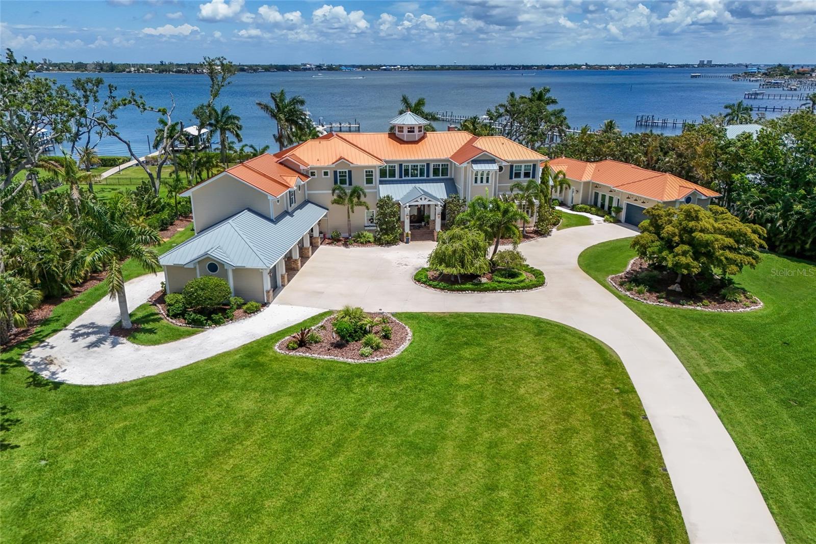 Introducing “VISTA DEL FIUME”, an ABSOLUTELY SPECTACULAR GATED MANATEE RIVER ESTATE situated on nearly 3 ACRES with deep water access and breathtaking panoramic views! Truly one of the most impressive private waterfront residences ever offered on the Manatee River!!! Tucked behind private gates and surrounded by impeccably manicured grounds, towering palms, lush tropical landscaping, expansive lawn space, private pond with fountain, and a full sport court, this extraordinary estate offers the ultimate blend of luxury, privacy, boating lifestyle, and resort style living. A long winding driveway leads to the stunning coastal inspired residence featuring Hardy Board siding, standing seam metal roof, Chicago brick accents, and over 7,000 sqft of meticulously crafted living space with 6 bedrooms, 6.5 bathrooms, and 6 covered parking spaces including a 5 car garage and porte cochere. Step through the grand front porch entry into a breathtaking great room where soaring ceilings, dramatic transom windows, custom millwork, and walls of glass perfectly frame the incredible river views while flooding the home with natural light. The open concept design seamlessly blends the great room, dining area, and kitchen into one extraordinary waterfront entertaining space. The chef’s kitchen is remarkable featuring dual oversized islands, dual refrigerators and freezers, Thermador 6 burner gas range with griddle, double dishwashers, farmhouse sink, prep sink, walk in pantry, custom two tone cabinetry, exposed wood beams, pendant lighting, and a charming sitting room overlooking the pool and river. Additional main level spaces include a private office, mudroom, elevator access, powder bath, incredible wine grotto with extensive storage, and a spectacular bonus/game room complete with full bar area, mini fridge, keg system, ice maker, sink, and accordion serving window opening directly to the outdoor entertaining areas. The luxurious primary suite is a true retreat featuring a private balcony overlooking the river, spa inspired bathroom with soaking tub and oversized walk in shower, dual vanities, and massive custom closets. Upstairs also includes three additional ensuite bedrooms, secondary laundry room, and dramatic hallways overlooking the great room and waterfront beyond. Above the garage you will find a beautifully finished mother in law suite, while a detached structure creates a true waterfront compound feel featuring an additional guest suite, full air conditioned gym, and tackle room. The home also features three laundry areas and surround sound throughout. The outdoor living experience rivals any private resort with multiple covered entertaining areas, brick flooring, roll down screens, outdoor kitchen, multiple dining and lounge spaces, gorgeous pool and spa overlooking the water, and a stunning firepit area positioned directly along the riverfront. Boaters will appreciate the exceptional composite dock with 9 foot wide walkway easily accommodating a golf cart, deep water access capable of accommodating large yachts and sailboats, and three lifts including 10,000 lb, 13,000 lb, and 30,000 lb lifts. Enjoy unforgettable sunsets from the dock, amazing sunrises from the house, endless outdoor entertaining, and one of the most breathtaking waterfront settings on Florida’s Gulf Coast. This is a once in a lifetime opportunity to own one of the finest luxury waterfront estates on the West Coast of Florida!
