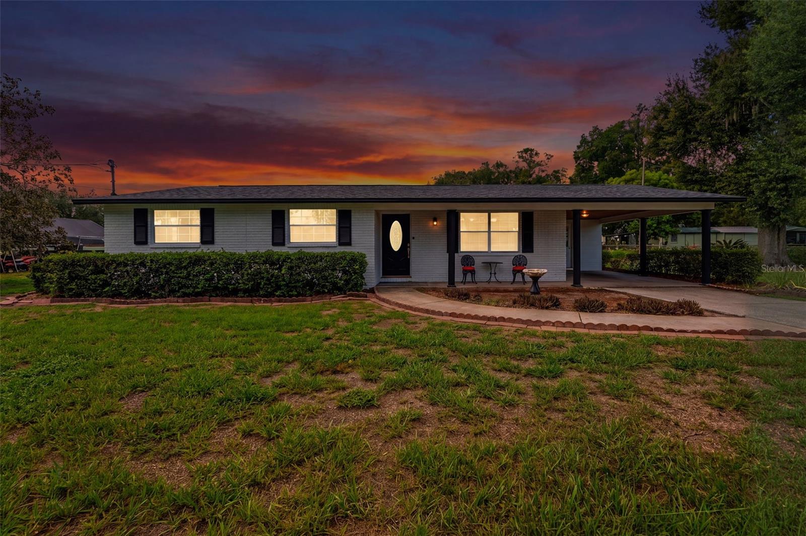 Classic 1968 painted-brick ranch on 1.6± fully usable acres in North Plant City — with its own private pond, no HOA, and Interstate-4 just up the road. A long concrete drive leads past mature oaks to a covered front porch, attached carport, and a lot that keeps going. Includes a three year old roof, detached steel carport, workshop/storage shed, fenced pen area for outdoor animals, and open green space rolling down to the water. Inside, a dated but incredibly maintained interior with an oversized living and dining room where an arched entry, chandelier, and wall of windows keep everything bright; sliders open to a screened lanai overlooking the back acreage. Bring the boat, the RV, the trailers, and every project on the list — with historic downtown Plant City and the Strawberry Festival minutes away, County Line Road putting I-4 at your doorstep, and an easy run to Lakeland or Tampa. Acreage like this, this close to the interstate, doesn't come around often.