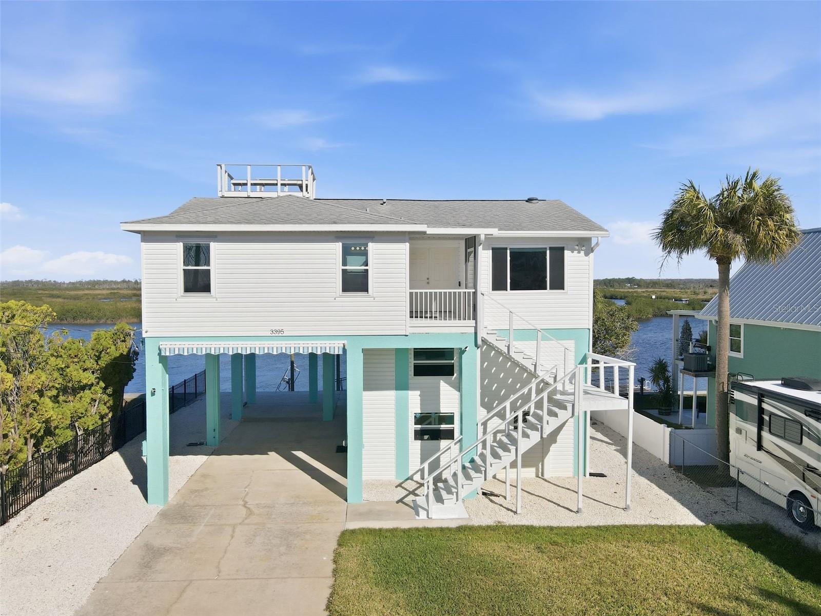 270 DEGREE SUNSET AND SUNRISE VIEWS OF THE GULF AND RIVER/MARSH FROM THE ROOFTOP CROWS NEST! YOU WILL NOT FIND A HOME WITH THIS VIEW FOR UNDER A MILLION DOLLARS! 2/2 open floorplan with AMAZING VIEWS FROM EVERY ROOM (except the laundry room) with an open-air porch in the front and screened-in porch in the back! Huge RV carport with 50-amp hookup and awning as well as an enormous enclosed workshop below this 16-foot-elevated home! Move in ready, everything has been done for you in the last 4 years including the seawall, 10K pound boat lift, dock, floating dock, IMPACT windows, HVAC, Kitchen including new appliances and custom granite, bathroom with enormous shower and granite counters, LVP flooring throughout, and a security system. Dolphins and manatees are often spotted! Just move in and enjoy a life most can only dream about.