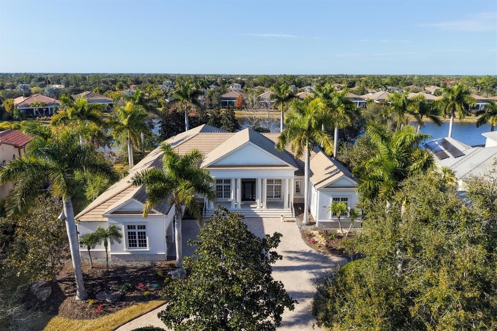 One or more photo(s) has been virtually staged. If you are looking for the BEST VALUE in the Lakewood Ranch, look no further than 7921 Waterton Lane, an exquisite luxury residence in the coveted gated community of THE LAKE CLUB in Lakewood Ranch, where timeless architecture, refined interiors, and shimmering lakefront views create a lifestyle of unmatched serenity and sophistication. Perfectly positioned on one of the community’s most serene streets—and former PRUETT MODEL ON MODEL ROW, walking distance to the world-class amenities! This meticulously maintained residence now offers FOUR bedrooms with their own bathroom!  The dedicated office could easily serve as a fifth bedroom option! From the moment you arrive, the home’s stately presence with circular drive, set the tone for the elegance that awaits inside. A grand foyer welcomes you with soaring ceilings, sun-splashed living spaces, and a seamless indoor–outdoor flow that celebrates Florida’s most coveted attribute: year-round resort-style living. The open-concept great room is framed by expansive impact glass sliders showcasing tranquil lake vistas, while refined architectural details—new feature wall with fireplace, crown moldings, coffered ceilings, new designer lighting, and new custom built-ins—enhance the home’s elevated aesthetic. The heart of the home is the gourmet chef’s kitchen, where top-tier appliances, including DOUBLE OVENS, WARMING DRAWER, A SUBZERO COMMERCIAL 2022 FULL REFRIGERATOR & FULL FREEZER, WINE CELLAR FOR 300 BOTTLES, rich cabinetry, a generous center island, new pendant lighting and a walk-in pantry come together to create both beauty and practicality. Whether hosting intimate dinners or entertaining large gatherings, this culinary space offers the perfect backdrop for unforgettable moments. Adjacent, the dining area and living room maximize lake views, creating a soothing ambiance that carries throughout the residence. The primary suite is nothing short of indulgent—complete with panoramic water views, generous sitting room with refreshed built-ins and MORNING BAR WITH DISWASHING DRAWERS MICROWAVE AND MINI FRIDGE, dual custom closets with custom built-ins, separate dressing areaand a spa-inspired bath featuring a large soaking tub, walk-in shower with dual shower heads, dual water closets and dual vanities. Step outside to your private lakefront oasis, where gentle breezes and sparkling water create a calming retreat. The sweeping lanai enhanced with travertine pavers and panoramic screens, offers covered lounging and dining areas, ideal for relaxing afternoons and sunset gatherings. With ample space for future enhancements, this outdoor haven invites you to savor Florida living at its best! Just beyond your doorstep lies everything The Lake Club is celebrated for. Enjoy a short walk to the grand clubhouse, private restaurant, resort pools, state-of-the-art fitness center, tennis facilities, vibrant pickleball courts, dog park and playground! Miles of walking trails, charming bridges, and stunning lakes weave throughout this master-planned paradise, placing luxury living and wellness at the forefront. 7921 Waterton Lane is more than a home—it is a lifestyle of elegance, convenience, and tranquility in Lakewood Ranch’s most elite enclave. Here, every detail has been curated for comfort, beauty, and connection to the breathtaking natural surroundings. Indulge in the privilege of lakefront living within one of Florida’s premier residential communities.
