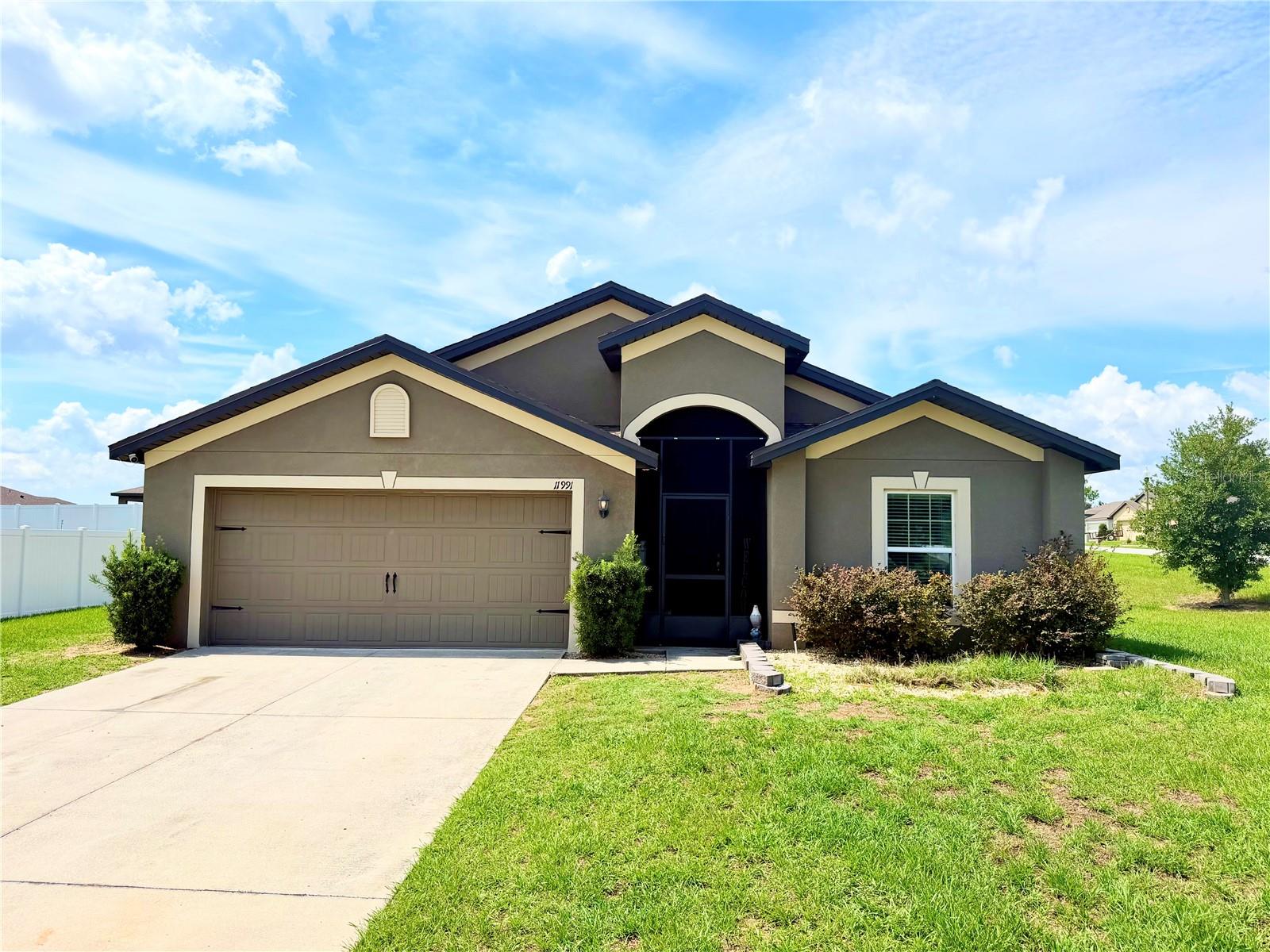 Welcome to this beautifully maintained 4 bedroom, 2 bathroom home located in the highly desirable Leesburg, Florida area, offering the perfect blend of modern construction, open concept living, and move in ready convenience. Built in 2021, this newer construction home features a spacious split bedroom floor plan, stylish finishes, and functional living spaces designed for both everyday comfort and entertaining. Situated on an oversized corner lot, the property provides additional outdoor space, excellent curb appeal, and a welcoming residential setting close to shopping, dining, schools, parks, and major Central Florida roadways.
From the moment you arrive, you’ll appreciate the large driveway, spacious 2 car garage, attractive front entry, and well maintained exterior. Inside, the bright and versatile layout offers a formal dining room or flex space that can easily function as a home office, sitting area, playroom, or additional living space depending on your lifestyle needs. The expansive open concept design creates seamless flow throughout the main living areas while allowing for abundant natural light.
The oversized kitchen serves as the centerpiece of the home and features granite countertops, stainless steel appliances, extensive cabinetry, pantry storage, bar seating, and a spacious eat-in dining area overlooking the large family room. The open layout is ideal for entertaining guests, hosting gatherings, or enjoying comfortable everyday living.
The spacious primary suite offers plenty of room for large furniture, including a king size bedroom set, and includes a private ensuite bathroom featuring dual vanities, a relaxing soaking tub, separate walk in shower, linen storage, and a large walk in closet. The split bedroom layout provides added privacy with three additional generously sized bedrooms and a full guest bathroom located on the opposite side of the home.
Step outside and enjoy the screened rear porch complete with mounted TV setup, creating the perfect year round outdoor living and entertaining space. The backyard also features a custom paver fire pit area ideal for relaxing evenings, entertaining friends, or enjoying Florida outdoor living.
Conveniently located near shopping centers, restaurants, schools, medical facilities, parks, and commuter routes, this move in ready Leesburg home offers modern upgrades, spacious living, outdoor entertainment space, and exceptional value. Whether you’re searching for a primary residence, family home, or newer construction property in Central Florida, this home checks all the boxes. (ROOF-2021)(A/C-2021)(W/H-2021)