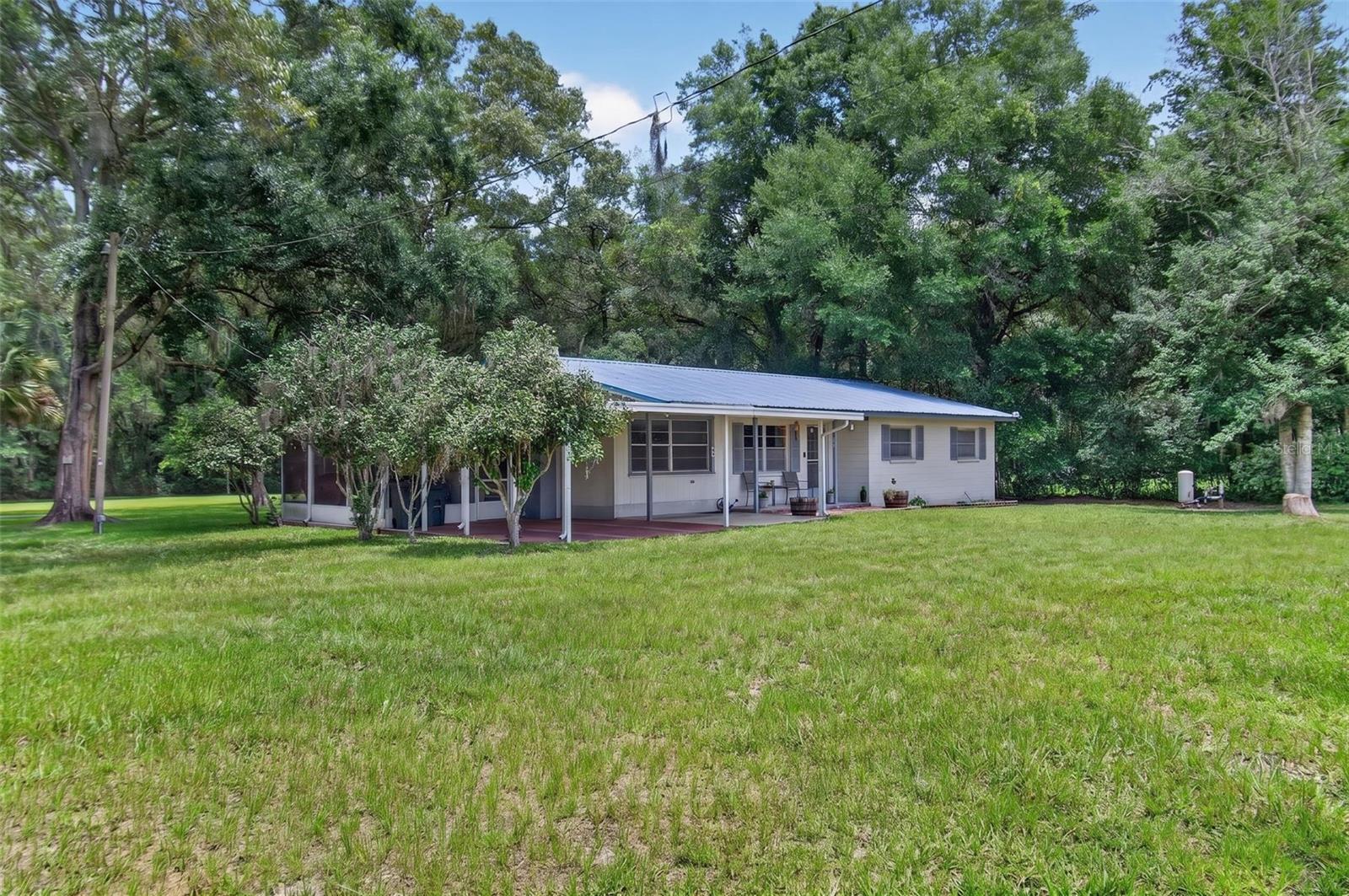 Welcome to country living at its finest! Situated on 1.38 beautifully landscaped acres, this charming 3-bedroom, 1-bath Ranch style home offers 1,628 heated square feet and 2,288 total square feet under a durable metal roof. Nestled among majestic oak trees, fruit trees, and mature landscaping, this property provides a peaceful park-like setting with plenty of room to enjoy the outdoors. The home features a spacious floor plan with a separate dining room, bonus room perfect for a home office, playroom, or hobby space, and an inside laundry room for added convenience.  Whether you're looking for a primary residence, a weekend retreat, or a place to enjoy Florida's natural beauty, this property delivers comfort, space, and privacy in a desirable Trenton location. Conveniently located at 7791 NW 165th Street, you'll enjoy the tranquility of country living while remaining close to area springs, the Suwannee River, shopping, dining, and local amenities. A rare opportunity to own a beautifully maintained home on acreage in North Central Florida!