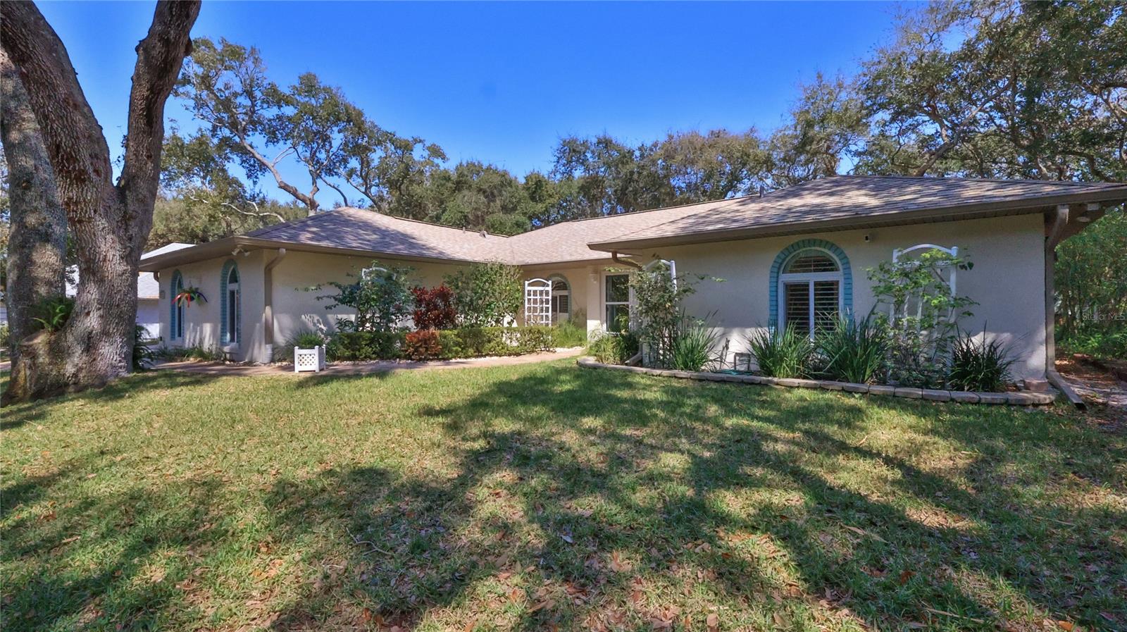Beautiful beachside 3 bedrooms with a split floor plan, 2 baths and a gorgeous open kitchen! When you pull in the driveway you can't help but notice all of the beautiful trees, the paver driveway and the pretty walk up to the front door. As you walk towards the front door you will pass two very special Scrub Oak "love trees" that are welcoming you to this home.
When you open the front door and walk into this home you will be standing in the Living Room which is adjacent to the dining room. As you look further into the home you will see the stunning, large, open kitchen, the breakfast nook and the spacious leisure room with 2 large skylights, a fireplace with a custom made Brazilian Cherry Mantel plus a triple sliding glass door that opens up to the backyard. The office is located to the right of the kitchen. Off of the kitchen is the laundry room which leads to the attached 2 1/2 car garage.
The Master bedroom is ensuite with a luxurious, custom shower complete will wall sprays, a pretty glass door & glass shelves for your artwork next to the shower, double sinks and an arch window that lets the sunshine on in and provides a wonderful view of the front yard! This home is located on top of a hill and it features a nice, high elevation, a large lot that measures 100' by 135', zoned A-1 and it is within the New Smyrna Beach City limits. The no drive portion of New Smyrna's beach is only about 3 blocks away.
Recent upgrades to this home include wind rated windows, sliders and skylights throughout, porcelain plank tile throughout the main living area and bathrooms, a full home Generx Generator, two stunning bathrooms, granite countertops in the kitchen and baths, plantation shutter and more. The two guest bedrooms are carpeted. Last but not least there is plenty of room to add a good size swimming pool and summer kitchen, if you desire.  Coastal Living is waiting for you here in New Smyrna Beach! Don't let this hidden treasure pass you by!! ;Water: City