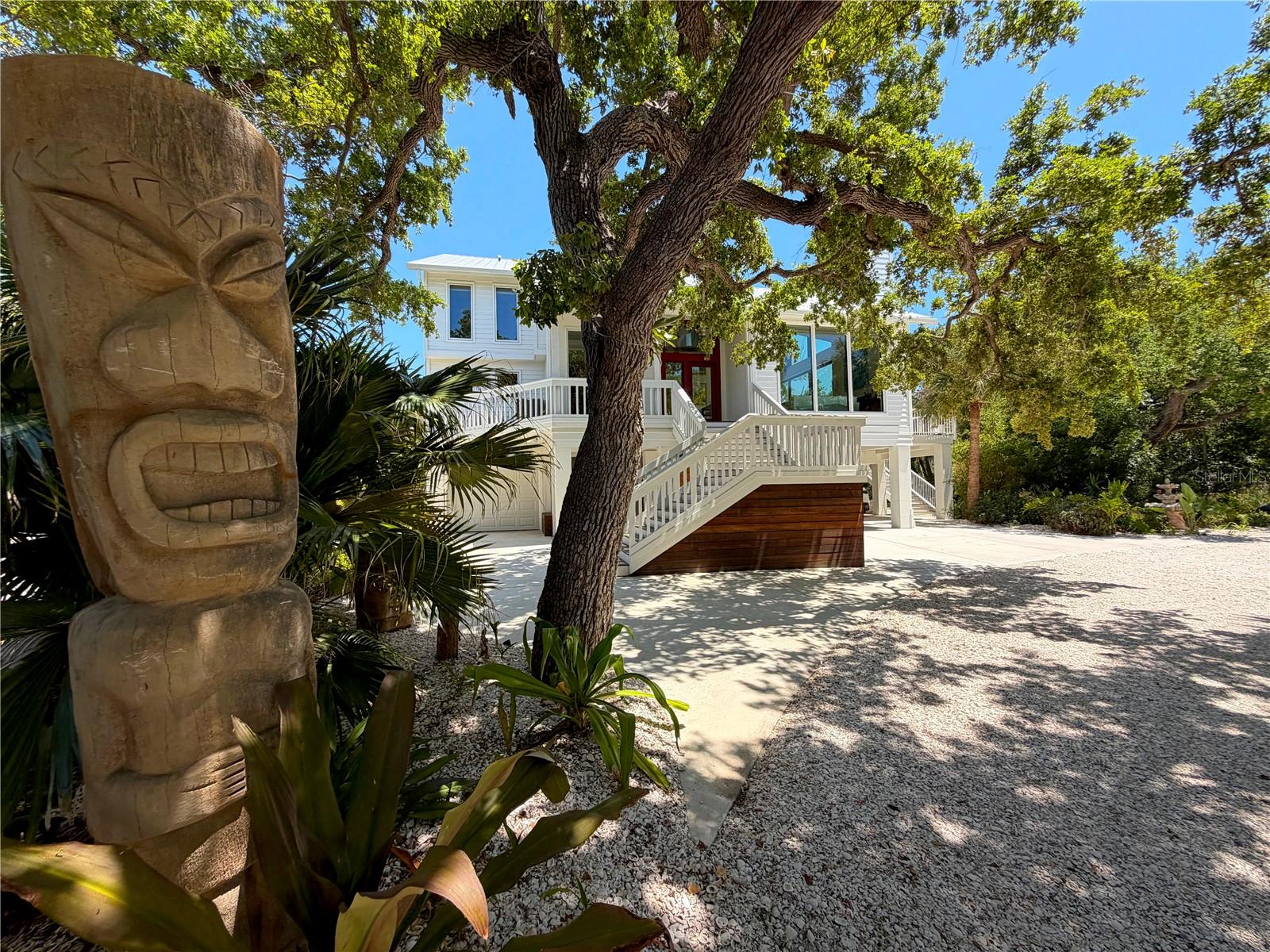 Rare bayfront acreage with deeded Gulf beach access on Manasota Key. Hidden behind a gated entrance and nestled among majestic live oaks, native palms, and lush tropical landscaping, this extraordinary coastal property offers a level of privacy and natural beauty seldom found on the island.

Designed to embrace its surroundings, the custom residence offers approximately 3,806 square feet of living space and more than 2,000 square feet of outdoor living areas. Expansive impact-rated windows and doors frame water views and fill the home with natural light, while premium European cabinetry, custom built-ins, and thoughtfully curated architectural details create an atmosphere that is both timeless and inviting.

The main living level opens seamlessly to an expansive covered lanai finished with porcelain tile that continues from the interior living spaces, creating effortless indoor-outdoor living. A spacious main-level suite with bay views, direct lanai access, custom closet systems, and a beautifully appointed bath provides exceptional flexibility for guests or multi-generational living. Upstairs, the primary suite enjoys direct access to the upper-level deck and rooftop observation deck, where panoramic views of Lemon Bay, the Intracoastal Waterway, and the Gulf of Mexico create an unforgettable backdrop.

Outdoor living is a defining feature of the property. Multiple levels of gathering spaces include covered and open-air decks, a ground-level entertainment pavilion, outdoor fitness and recreation areas, and a 10' x 8' spa. A private boardwalk winds through the natural shoreline landscape to the water's edge, connecting a series of waterfront destinations and a bayfront platform overlooking Lemon Bay.

Ownership includes natural shoreline areas and submerged lands extending into Lemon Bay, creating a unique private waterfront setting rarely found on Manasota Key. Deeded Gulf beach access is located directly across the street, offering the best of both worlds—sunrise views across the bay and sunsets over the Gulf.

Additional features include impact-rated windows and doors, high-efficiency mechanical systems, extensive insulation and air sealing, tankless propane water heating, and a landscape carefully preserved to enhance privacy, beauty, and connection to the surrounding environment.

Whether entertaining beneath the live oaks, enjoying the rooftop views, relaxing by the water's edge, or strolling the private boardwalk, this is a property that offers an experience as unique as its setting.