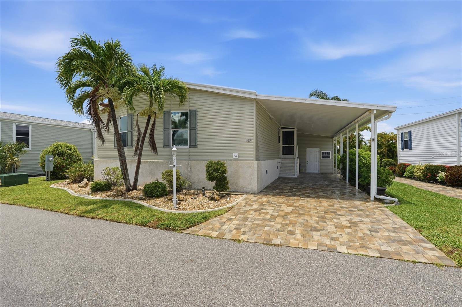 Discover easy Florida living in this beautifully maintained manufactured home located in the desirable 55+ waterfront community of Windmill Village in Punta Gorda. Offering 2 bedrooms, 2 bathrooms, plus a versatile den, this home features an inviting open layout, vaulted ceilings, and comfortable indoor-outdoor living spaces designed for relaxation and entertaining. Surrounded by lush landscaping and located in a vibrant resident-owned community, this property is perfect for enjoying the Southwest Florida lifestyle. Shares are included in the sale price, adding exceptional value and ownership benefits.

RESIDENCE OVERVIEW:
• 2 Bedrooms | 2 Bathrooms | Plus Den
• Shares included in sale price
• Located in the 55+ resident-owned community of Windmill Village
• Open-concept living and dining layout
• Vaulted ceilings
• Vinyl flooring throughout main living areas
• Screened lanai and spacious yard
• Covered carport with attached storage room

INTERIOR FEATURES:
• Bright and inviting layout with abundant natural light
• Vaulted ceilings creating an open and airy feel
• Vinyl flooring throughout main living spaces
• Open living and dining room design
• Glass slider leading to the screened lanai
• Comfortable flow ideal for entertaining and everyday living

CULINARY SPACE:
• All appliances included
• Center island with breakfast bar seating
• Ample cabinetry and counter space
• Open connection to living and dining areas

PRIVATE OWNER’S RETREAT:
• Spacious primary bedroom
• Large built-in closet
• Private en-suite bathroom featuring:
– Dual sink vanity
– Dedicated makeup space
– Walk-in shower

GUEST ACCOMMODATIONS:
• Guest bedroom with built-in closet
• Nearby full guest bathroom for family and visitors

VERSATILE FLEX SPACE:
• Den ideal for:
– Home office
– Media room
– Hobby or craft space
– Additional guest room

OUTDOOR LIVING:
• Screened lanai perfect for relaxing outdoors
• Spacious yard surrounded by serene lush landscaping
• Peaceful setting ideal for enjoying the Florida weather year-round
• Attached storage room located in the carport for added convenience

COMMUNITY HIGHLIGHTS – WINDMILL VILLAGE:
• Resident-owned 55+ waterfront community
• Community clubhouse with social activities and events
• Heated marina-front pool
• Recreation hall, library, billiards, and fitness areas
• Bocce ball, shuffleboard, horseshoes, and picnic areas
• Private marina with boat slips and access to Peace River and Charlotte Harbor
• Active community atmosphere with organized clubs and activities
• Conveniently located near downtown Punta Gorda shopping, dining, waterfront parks, Fishermen’s Village, golf courses, and medical facilities

A wonderful opportunity to enjoy low-maintenance living in one of Punta Gorda’s sought-after active adult communities with fantastic amenities, waterfront access, and a welcoming neighborhood atmosphere.