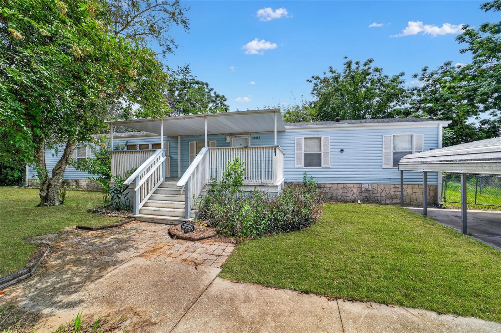 Enjoy relaxed, country-style living in this charming 3-bedroom, 2-bath split-plan home in Belleview Hills Estates, a community where you own the land and there’s no HOA. Set back from the road for added privacy, the home welcomes you with a large covered front deck, an ideal spot for morning coffee or unwinding outdoors. Inside, the split-bedroom layout offers comfortable separation, complemented by cathedral ceilings in the living room that create an open, airy feel. The spacious kitchen provides abundant cabinetry, a center island, and a conveniently tucked-away laundry closet with storage shelving. The primary suite features high ceilings, a generous walk-in closet, and an en suite bath with double vanities, a walk-in shower, and a separate garden tub. The secondary bedrooms each offer a walk-in closet, and an impressive 12' x 32' covered screen room provides great space perfect for hobbies, gatherings, or extra lounging space. A roomy carport and parking pad offer dedicated vehicle space, while the large, fenced backyard with two storage sheds provides plenty of room for outdoor enjoyment. Located just a short drive from The Villages with easy access to I-75, this home offers both convenience and a peaceful setting. With space, flexibility, and the freedom to make it your own, this property is ready to be the next chapter in your Florida lifestyle.