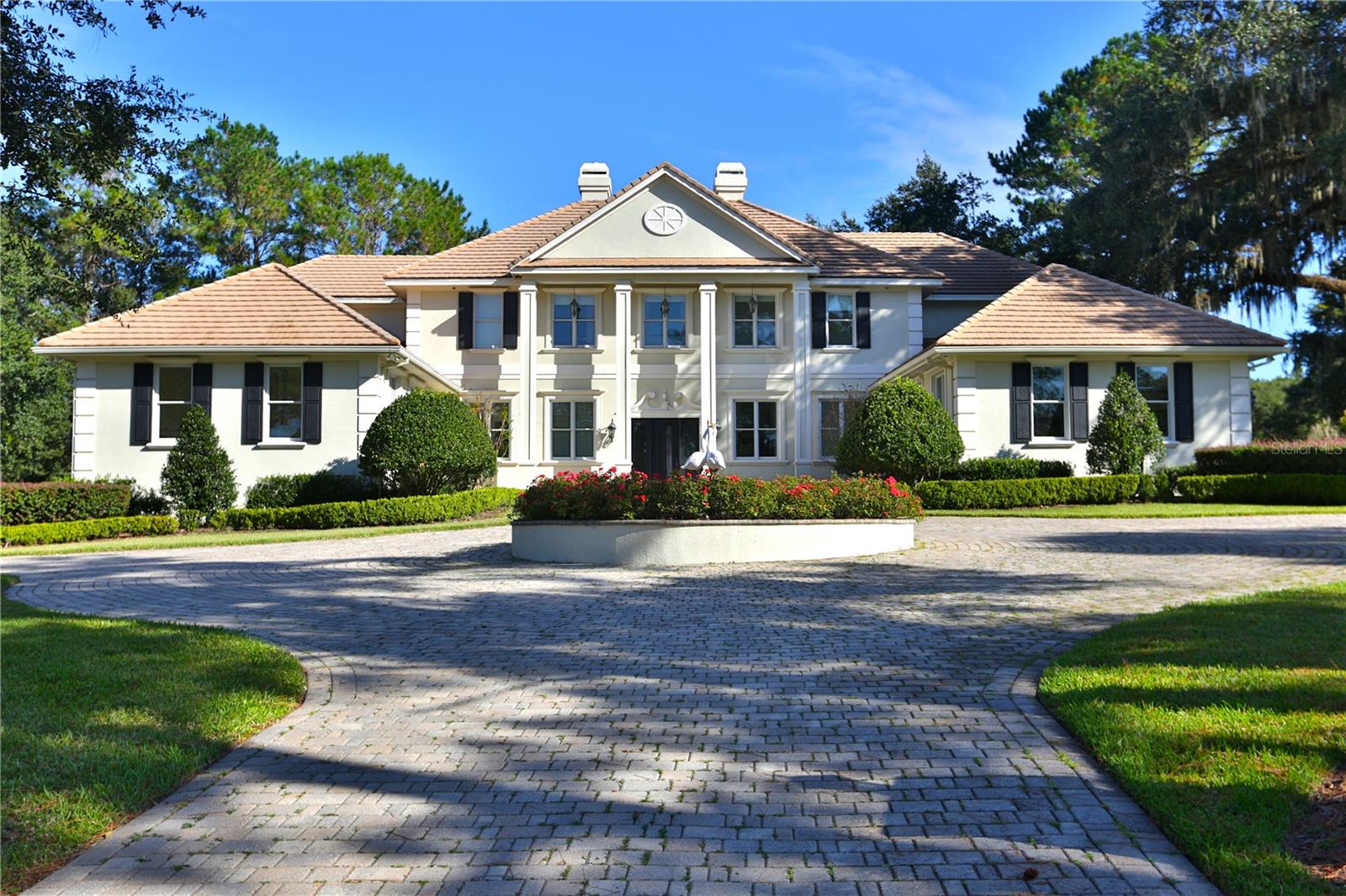 Nestled on the challenging 15th green of the Golden Ocala Golf Course, this stunning estate offers breathtaking views of the course, bridge, and pond. A circular driveway with pavers and a fountain welcomes you to this impressive two-story home. 
As you enter, the floor-to-ceiling windows offer stunning views of the pool and golf course. Lavishly appointed, this stately residence features approximately 5,912 square feet of living space, with options for five or six bedrooms, five full baths, and one half bath.
The beautiful formal living room features a double-sided fireplace, soaring ceilings, expansive walls, and French doors that open to the pool area, offering incredible views. The formal dining room features a butler's bar, a fireplace, and a wall of windows that fill the space with natural light while showcasing the same stunning views.
The chef's kitchen is equipped with Wolf double ovens, a Sub-Zero refrigerator, a Wolf gas cooktop, and a center island complete with a prep sink, two refrigerator drawers, and a microwave. The main island includes dual sinks, two dishwashers, and a raised bar area for additional seating. Nearby, an informal dining alcove with large windows provides a delightful space for family breakfasts. This charming kitchen opens to the family room, serving as the home's central gathering area.
The owner's suite on the first floor boasts a sitting area, dual walk-in closets, and French doors leading to the pool and covered lanai. The spacious bath offers dual sinks, a soaking tub, and a large private shower. An adjacent room can serve as an office, nursery, gym, or any other purpose you choose.
A private elevator or staircase leads to the second floor, which is divided into two wings. One wing features a conversation or TV area with a mini refrigerator and sink, along with bedrooms two and three, both of which are en-suites. The other wing contains bedrooms four and five, equipped with private dual vanity areas and a shared bath. A bonus room on this level could serve as a playroom or an additional bedroom. Two of the upstairs bedrooms open to private balconies that overlook the pool, pond, and 15th hole.
Enjoy the covered lanai, summer kitchen, and beverage bar, which provide ample seating and conversation areas surrounding the pool. Alternatively, you can unwind in the adjoining shade garden. The home features two garages, each accommodating two cars, with one offering easy access to the kitchen and the other serving the owner’s wing.
Enjoy the covered lanai, summer kitchen, and beverage bar, which provide ample seating and conversation areas surrounding the pool.  Alternatively, you can unwind in the amenities at Golden Ocala, which include a clubhouse, pool, tennis courts, a fitness center, a spa, and both casual and fine dining options. With access to the World Equestrian Center just a golf cart ride away, you can enjoy various activities and horse events, dine at exquisite restaurants, visit with friends, and explore nearby shops.