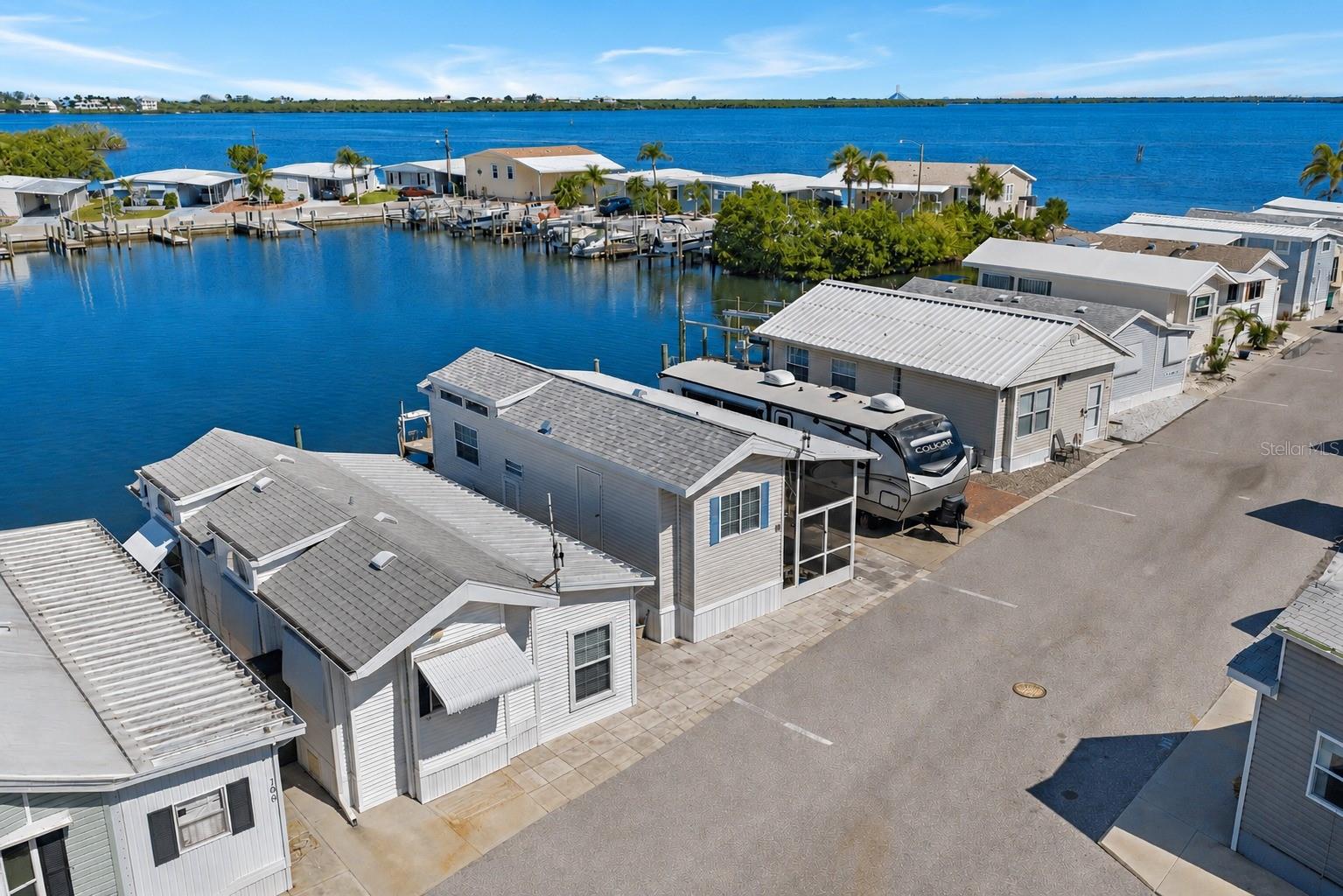 WATERFRONT BOATER’S PARADISE IN TROPIC ISLES! Experience the Florida Gulf Coast lifestyle in this charming 2003 park model home located on a basin-front lot in the highly sought-after 55+ resident-owned community of Tropic Isles. Just minutes by boat to Terra Ceia Bay and the Manatee River, this property is perfect for boating enthusiasts, anglers, and anyone who loves life on the water.
Inside, you'll find 1 bedroom, 1 bathroom, and a bright, open living space with stunning basin views. Large windows fill the home with natural light, creating an airy feel that lives larger than its footprint. New shingle roof installed in 2025. Enjoy your morning coffee while watching boats glide by. The western exposure offers unforgettable sunsets, creating the perfect backdrop for relaxing evenings by the water.  A screened porch addition along the north side of the home expands the living space outdoors, providing a shaded retreat to enjoy Florida's coastal breezes, waterfront views, and year-round outdoor living in comfort. 
Bring your boat and take advantage of your private slip right outside your door for quick and easy access to open water. An indoor laundry area adds everyday convenience.  Tropic Isles offers an exceptional waterfront lifestyle with amenities including a full-service marina, bait shop, heated pool and spa, fitness room, library, shuffleboard courts, social halls, and an active calendar of community events and activities. The low monthly maintenance fee of just $372 provides access to these outstanding amenities and an active Gulf Coast lifestyle. Whether you're looking for a seasonal getaway or year-round waterfront living, this rare opportunity delivers affordable boating access and endless coastal charm. Schedule your private showing today!